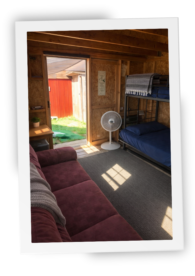 A retreat cabin interior at HorseSpeak with bunk bed, sofa, and open door looking out to the ranch.