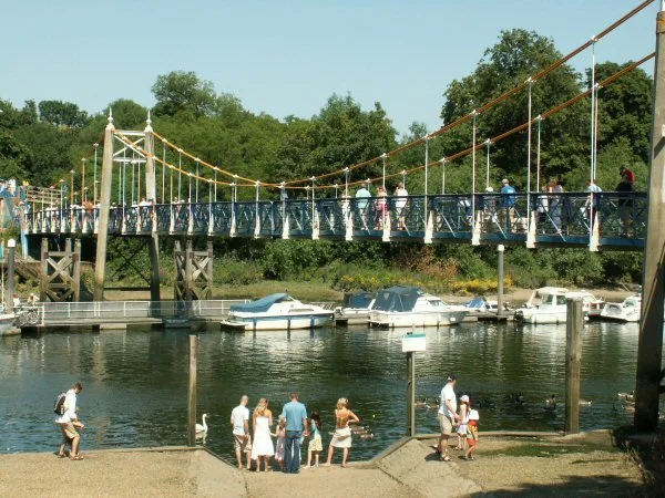 Teddington lock footbridge over the river with people on the foreshore