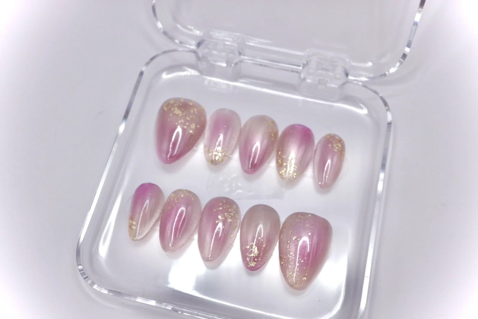 Set of ten pink and gold nail art tips in a clear plastic case.