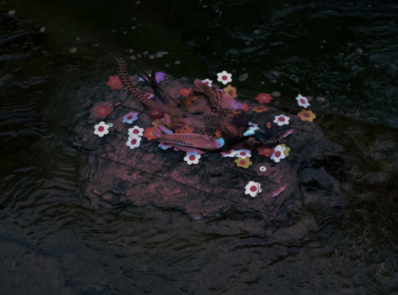 A fish is caught on a makeshift raft decorated with colorful paper flowers, floating in dark water.