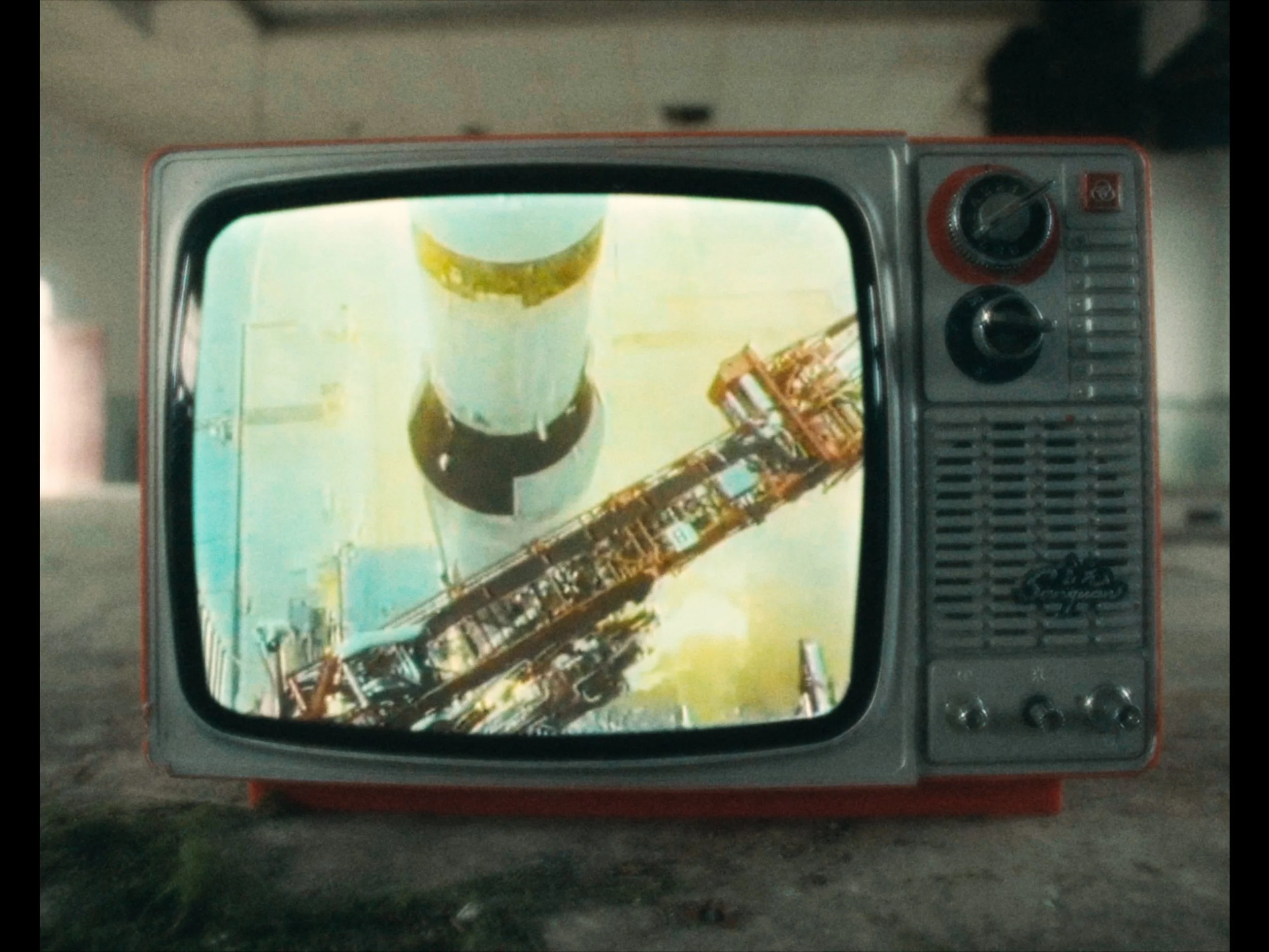 A vintage TV set displaying an aerial view of oil refineries with storage tanks and processing equipment.
