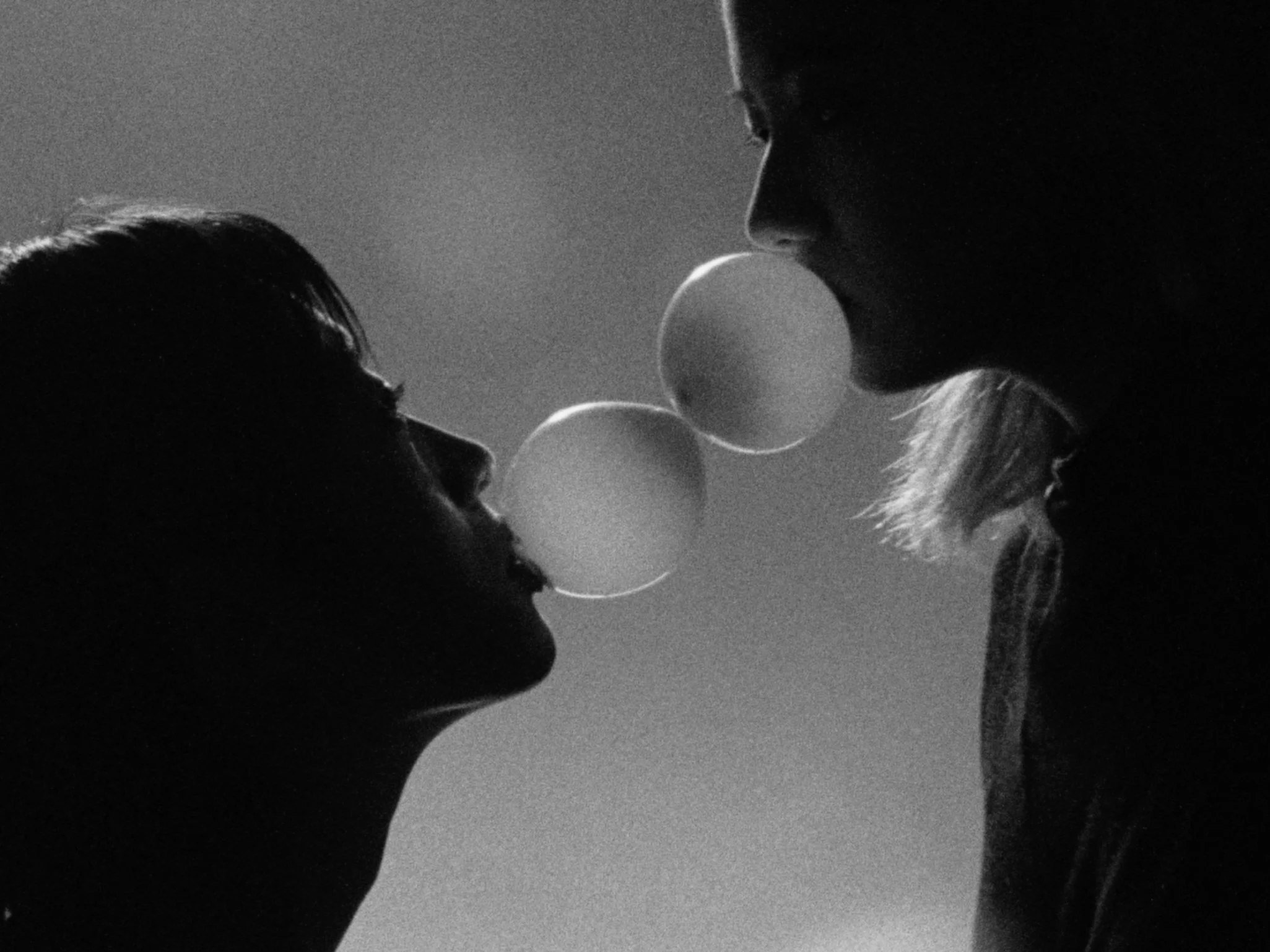 Silhouettes of two people facing each other, blowing bubbles in black and white.