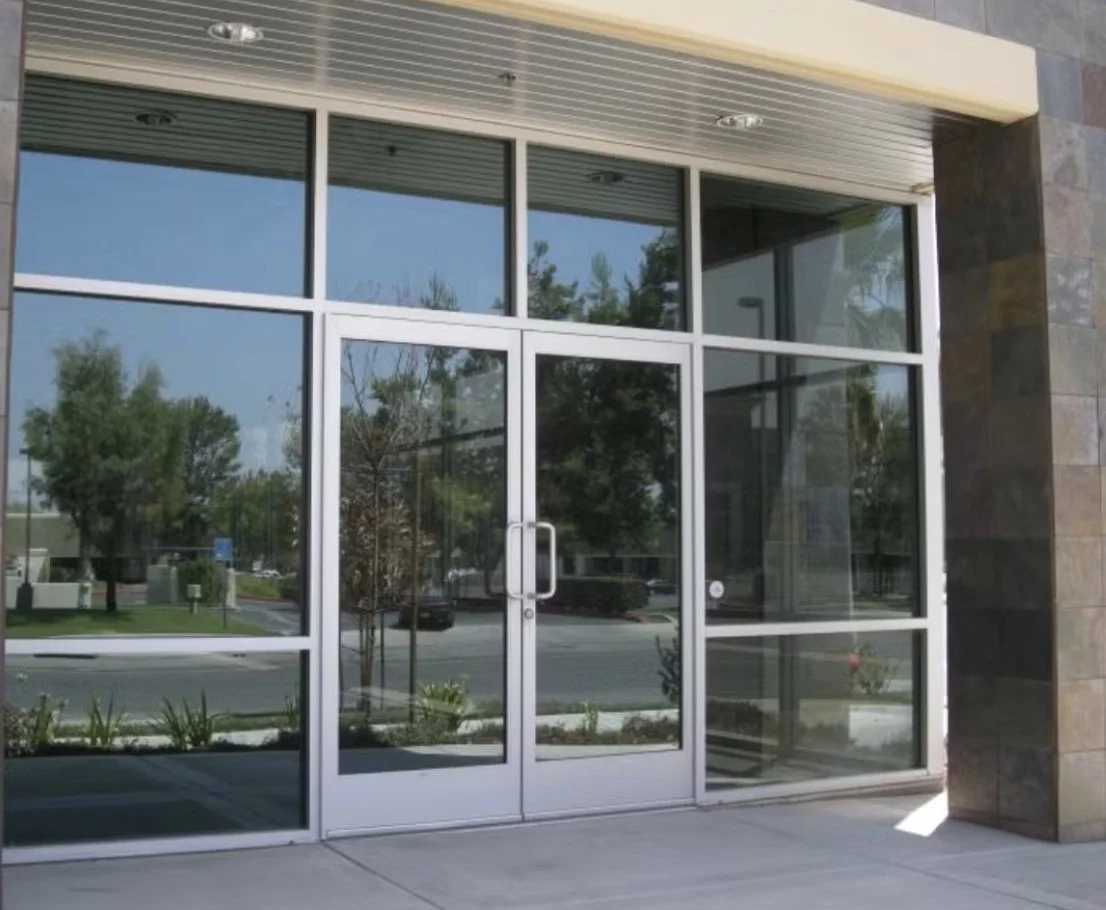 Interior bathroom scene with a closed glass door, towel racks, and a vanity with toiletries and decor.