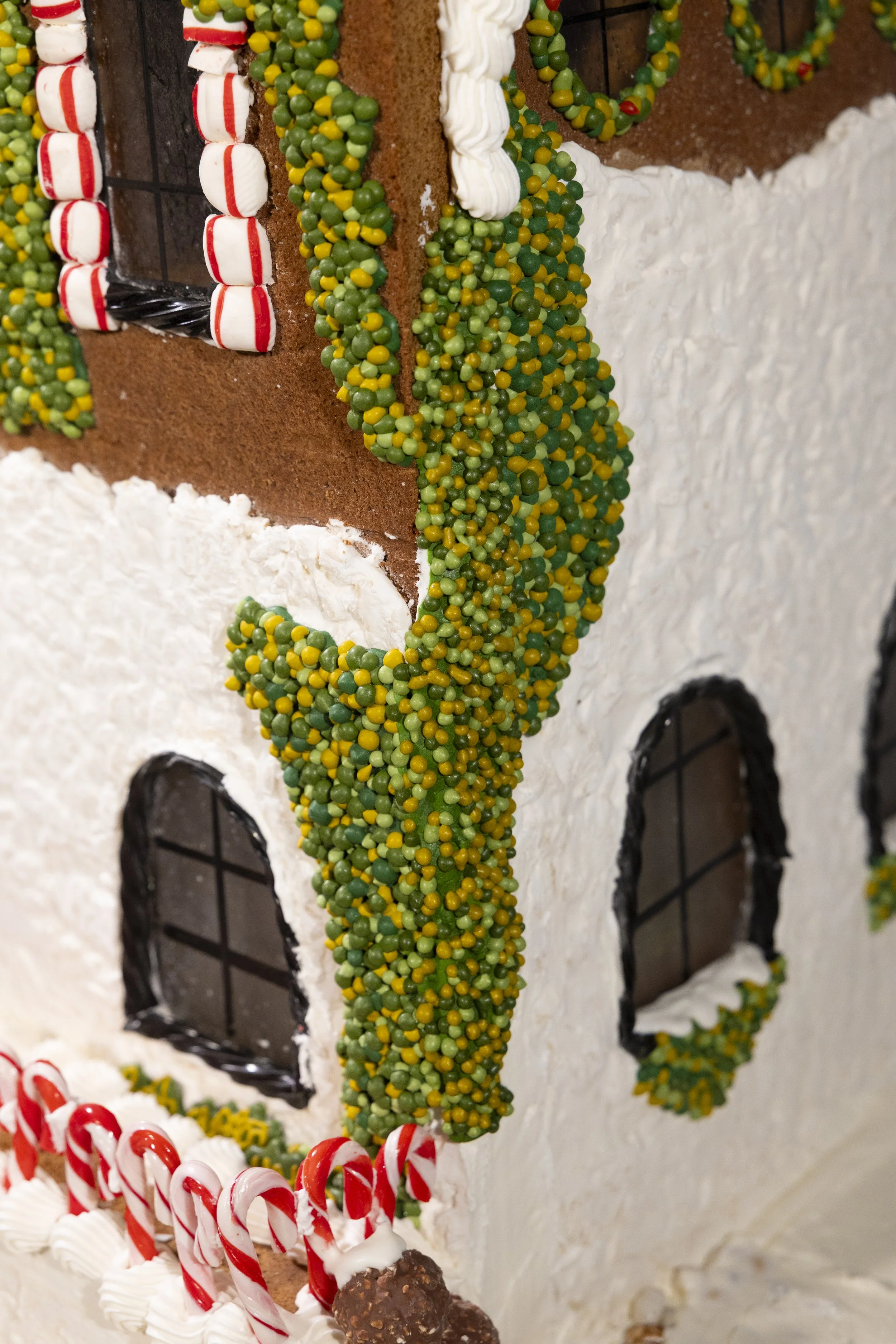 Christmas-themed gingerbread house decorated with candy canes, icing, and gumdrops.