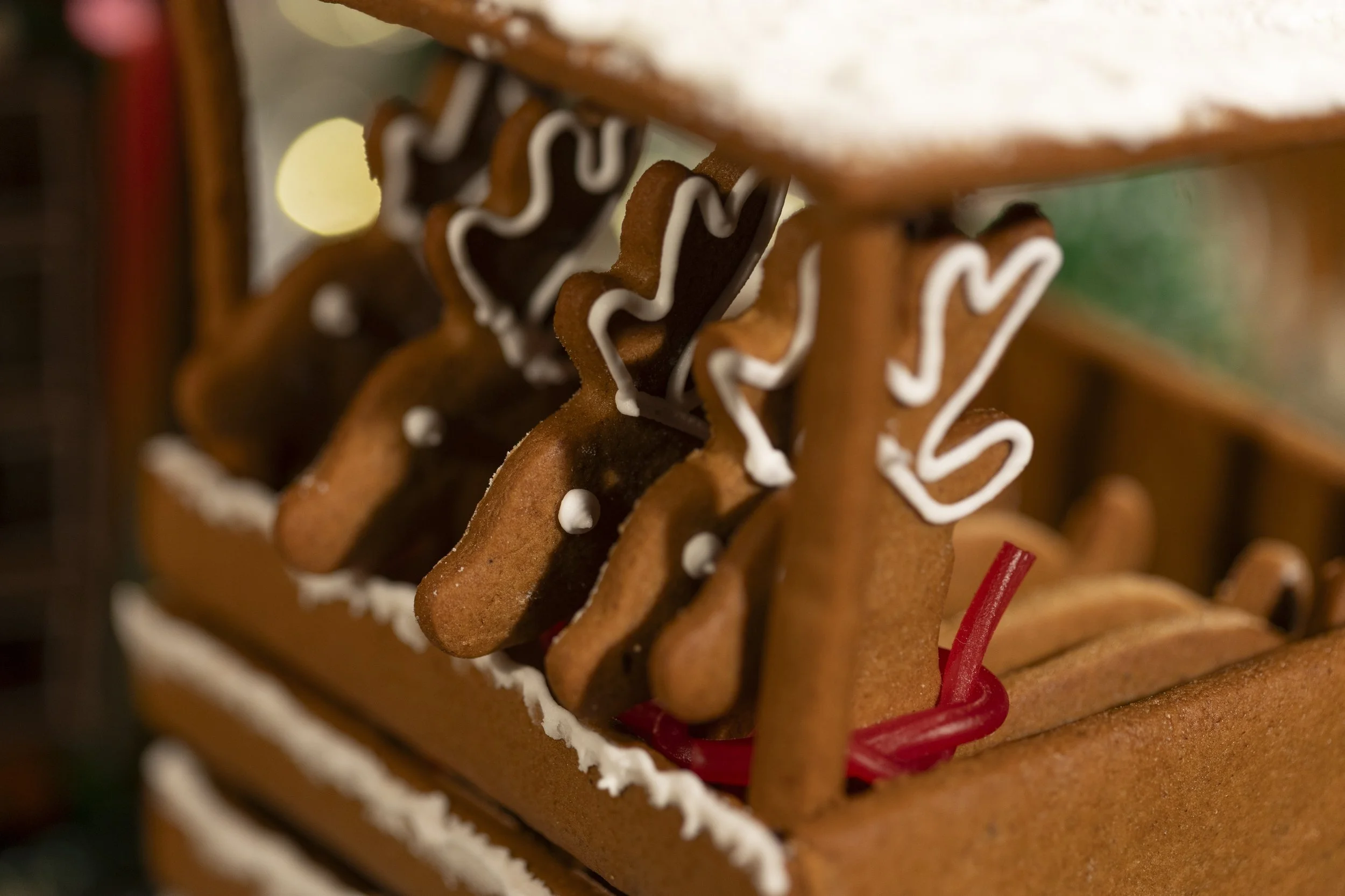 Decorative gingerbread cookies with white icing, shaped like reindeer, hanging on a rack.