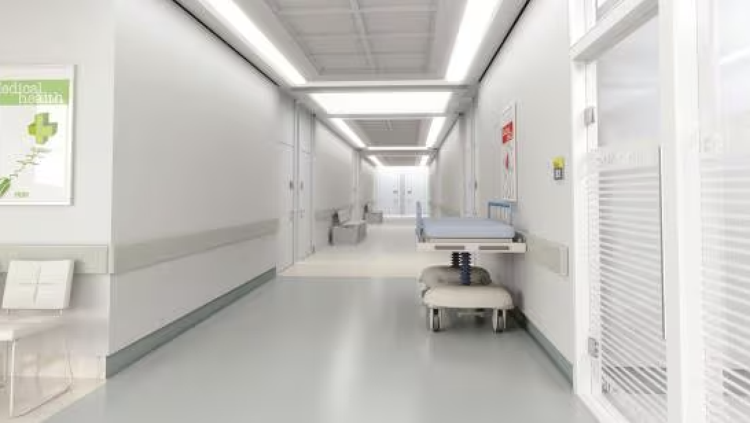 Empty hospital corridor with patient beds and medical equipment along the walls.
