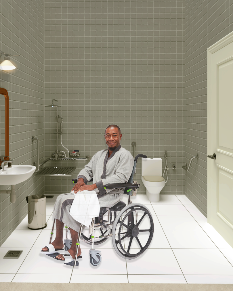 A man in a wheelchair sitting in a bathroom with tiled walls, a sink, a toilet, and a shower area.