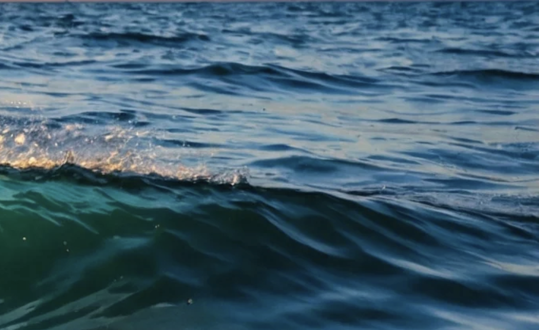 Calm ocean waves with sunlight reflecting on the surface.