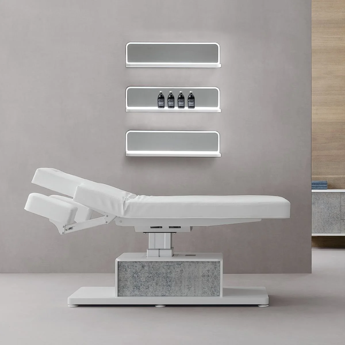 Una sala medica con un lettino bianco e scaffali con bottiglie di farmaci o prodotti farmaceutici sullo sfondo.