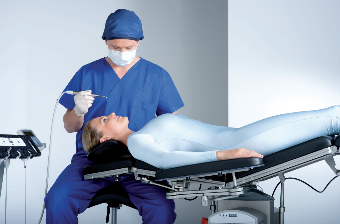 Medico in abbigliamento chirurgico che assiste una paziente distesa su un tavolo operatorio