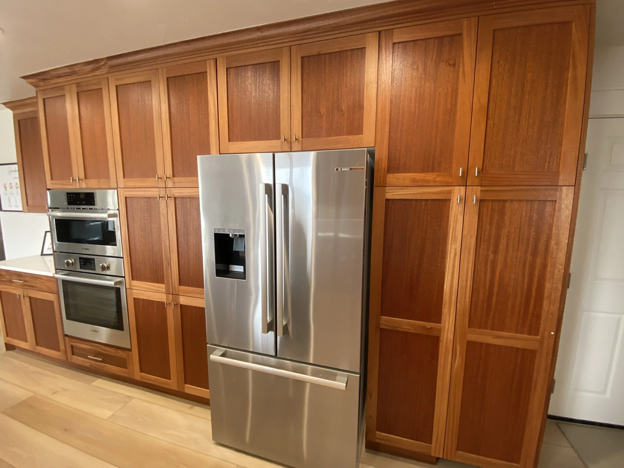 Kitchen with wooden cabinets, stainless steel refrigerator, and built-in oven and microwave.