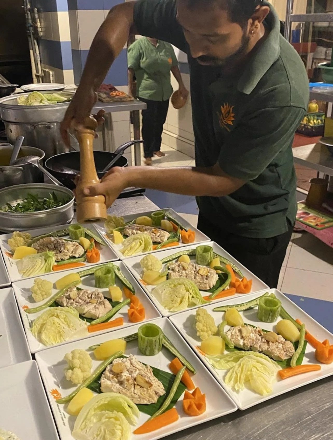 Šéfkuchař ochucuje zeleninu a maso při přípravě servírování v kuchyni – inspirace pro ájurvédskou gastronomii a kulinářské zážitky během wellness pobytu.