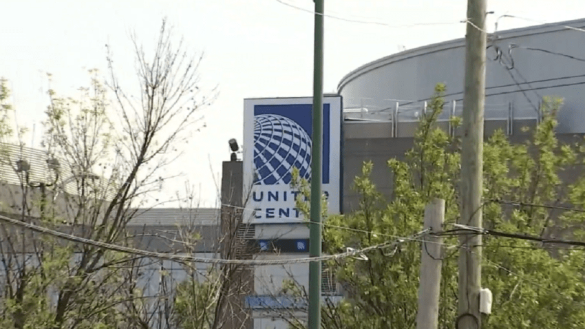A sign for the United Center, with some trees and utility poles and wires in the foreground.
