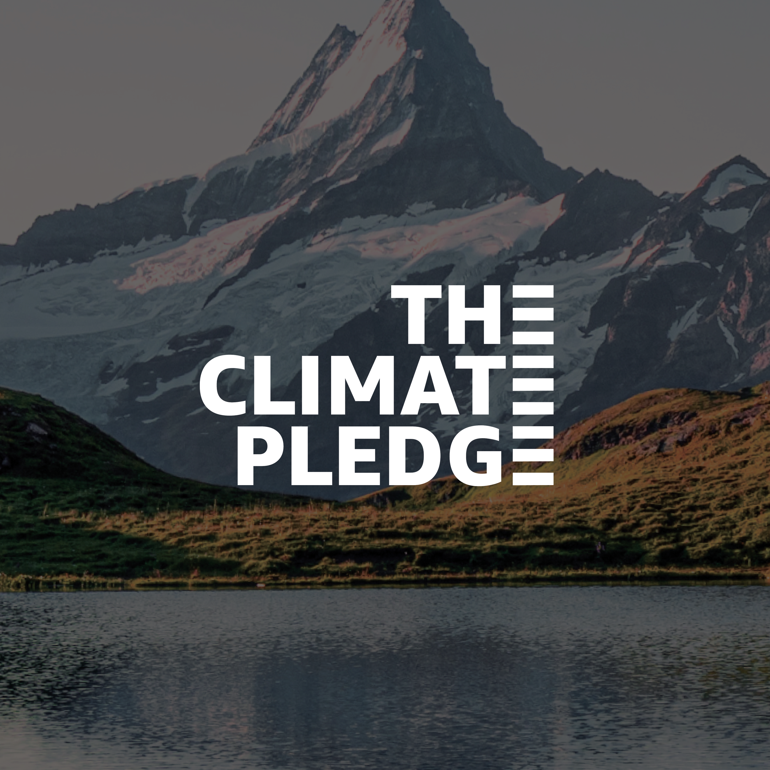A scenic mountain landscape with a snow-capped peak, green grassy hills, and a calm lake in the foreground with the text 'The Climate Pledge' overlaid.