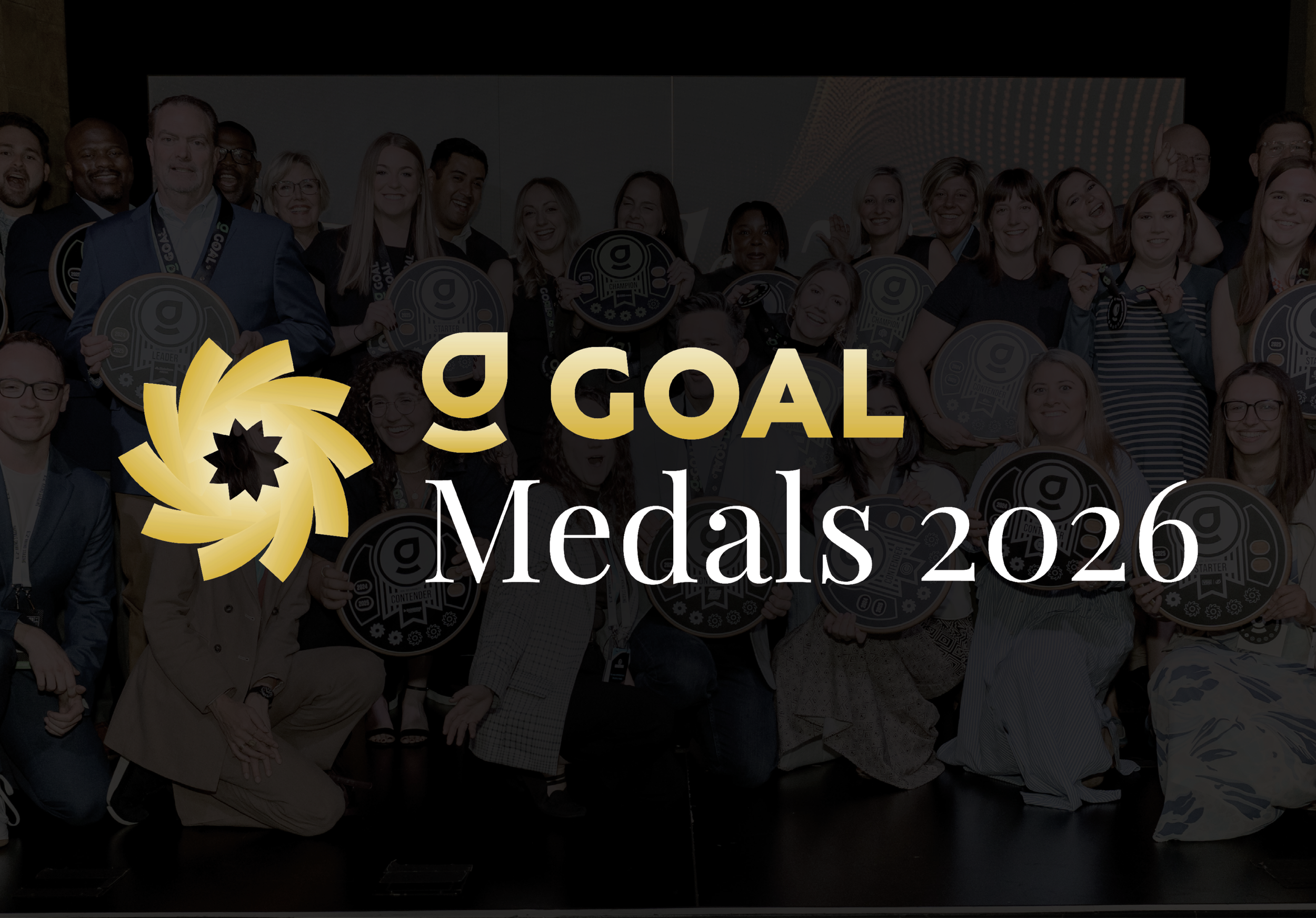 Group of people at an award ceremony holding circular medals and awards, with a large overlay text reading 'G GOAL Medals 2026' and a gold and black logo.
