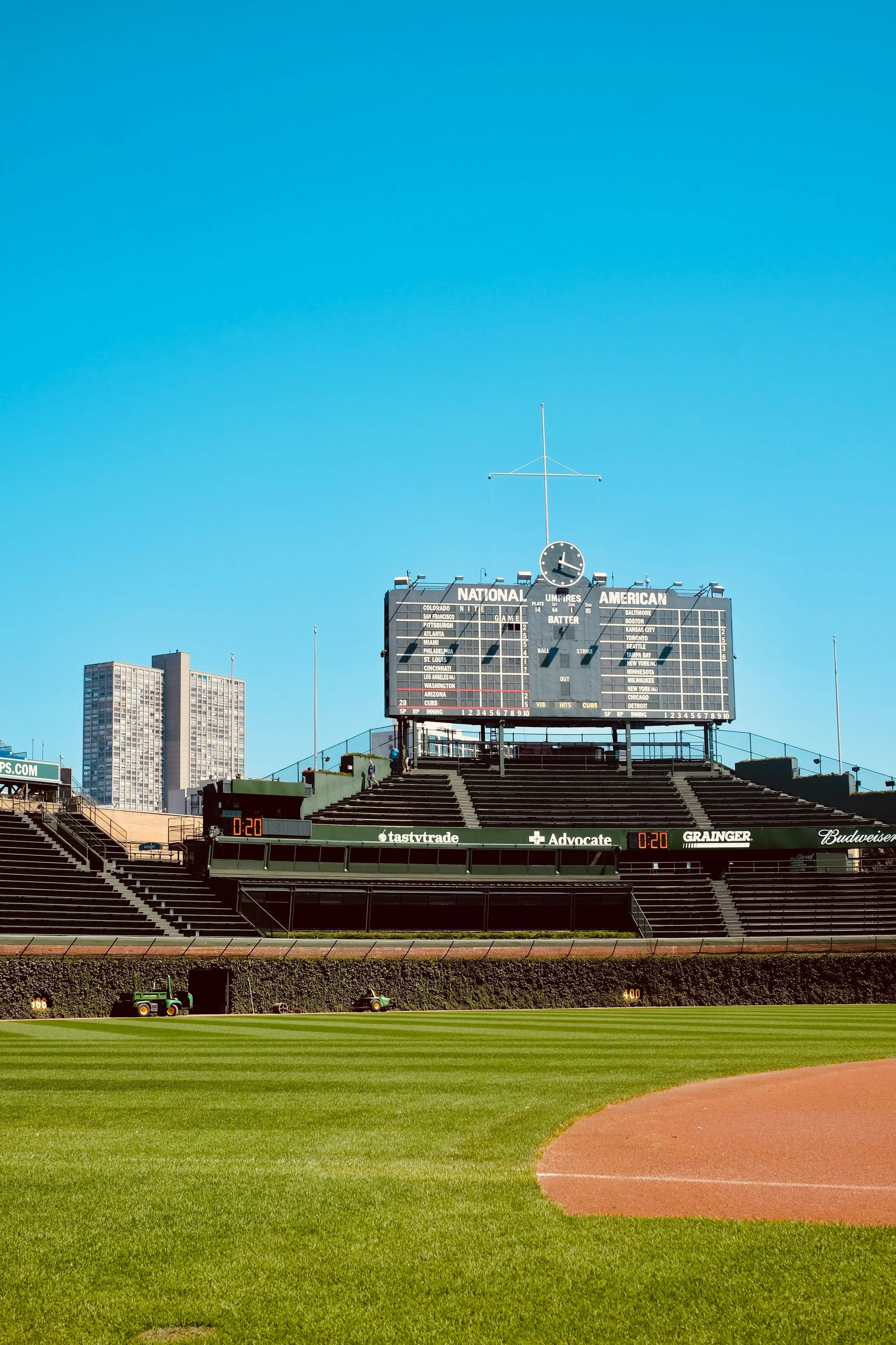 Empty baseball stadium with a scoreboard and field under a clear blue sky.