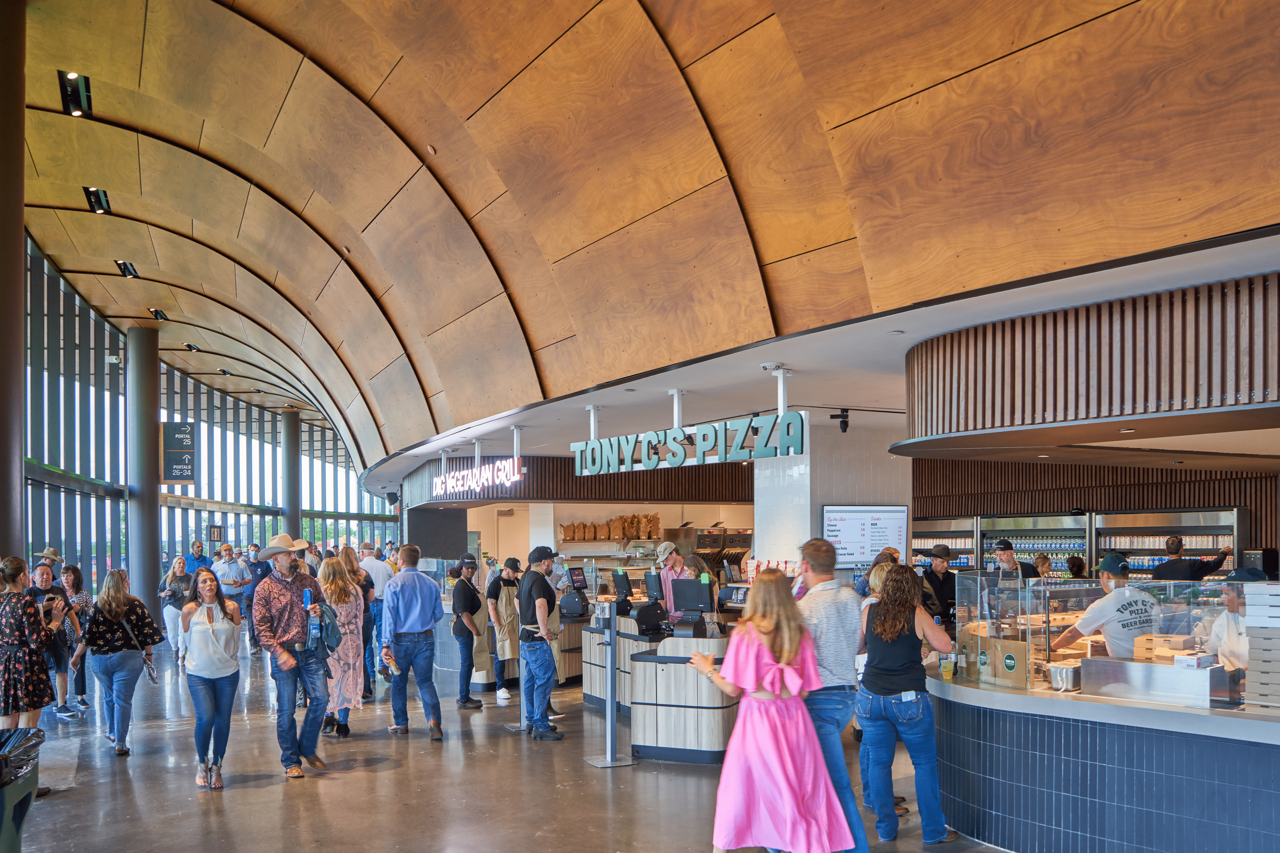 Inside a busy food court with a pizza counter named "Tony C's Pizza" and people waiting in line or walking around.