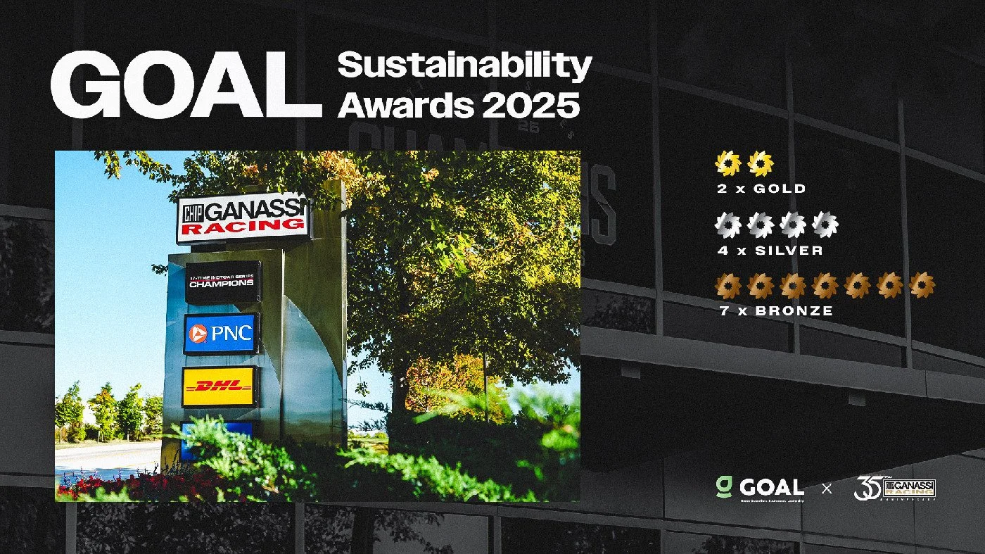 A sign in front of trees with logos of Chip Ganassi Racing, PNC, and DHL, under a clear blue sky.