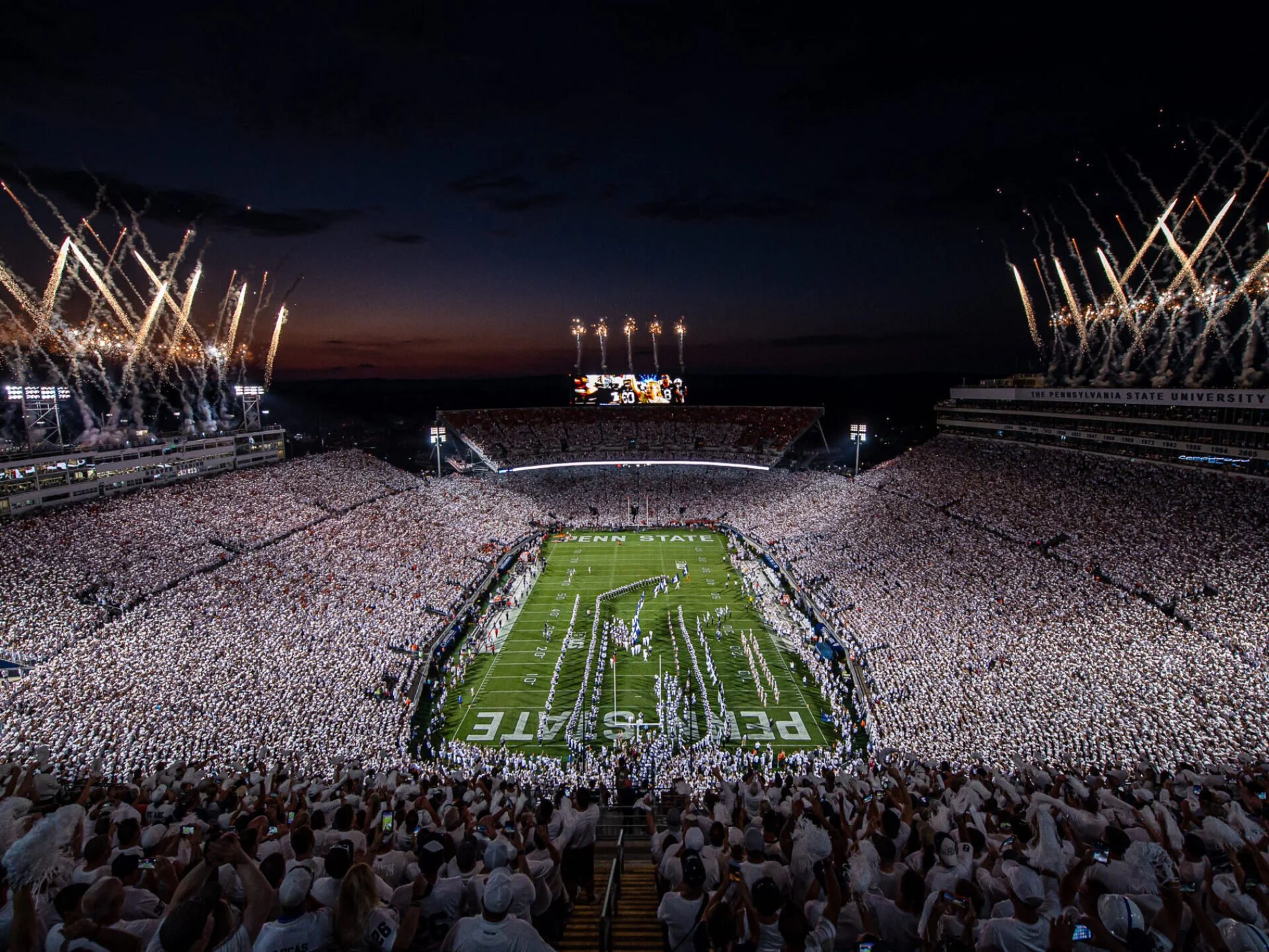 A nighttime scene of a packed college football stadium with fireworks lighting up the sky for Penn State University.