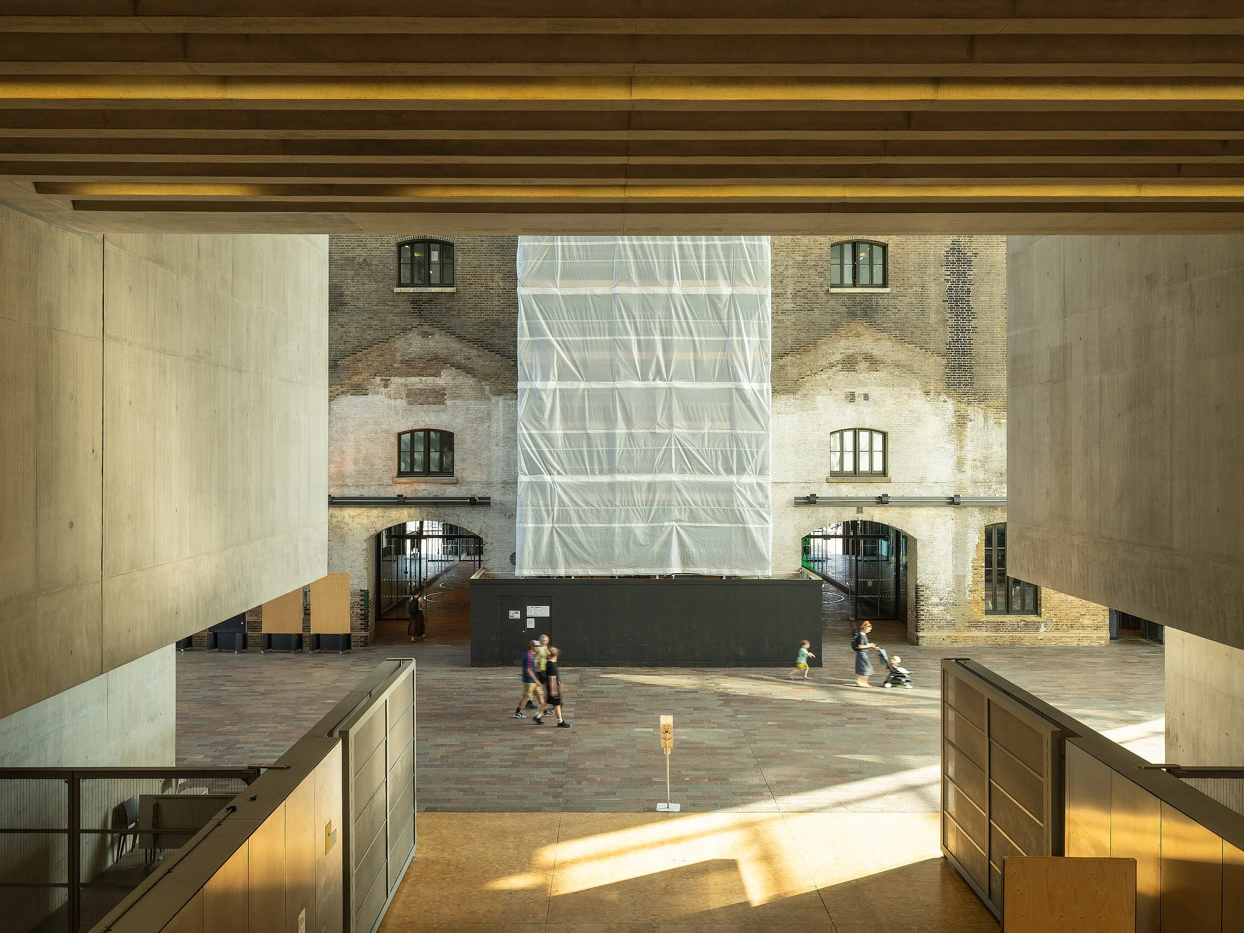 People walking through the main public passageway in Central Saint Martins built for UAL by Stanton Williams at Sunset