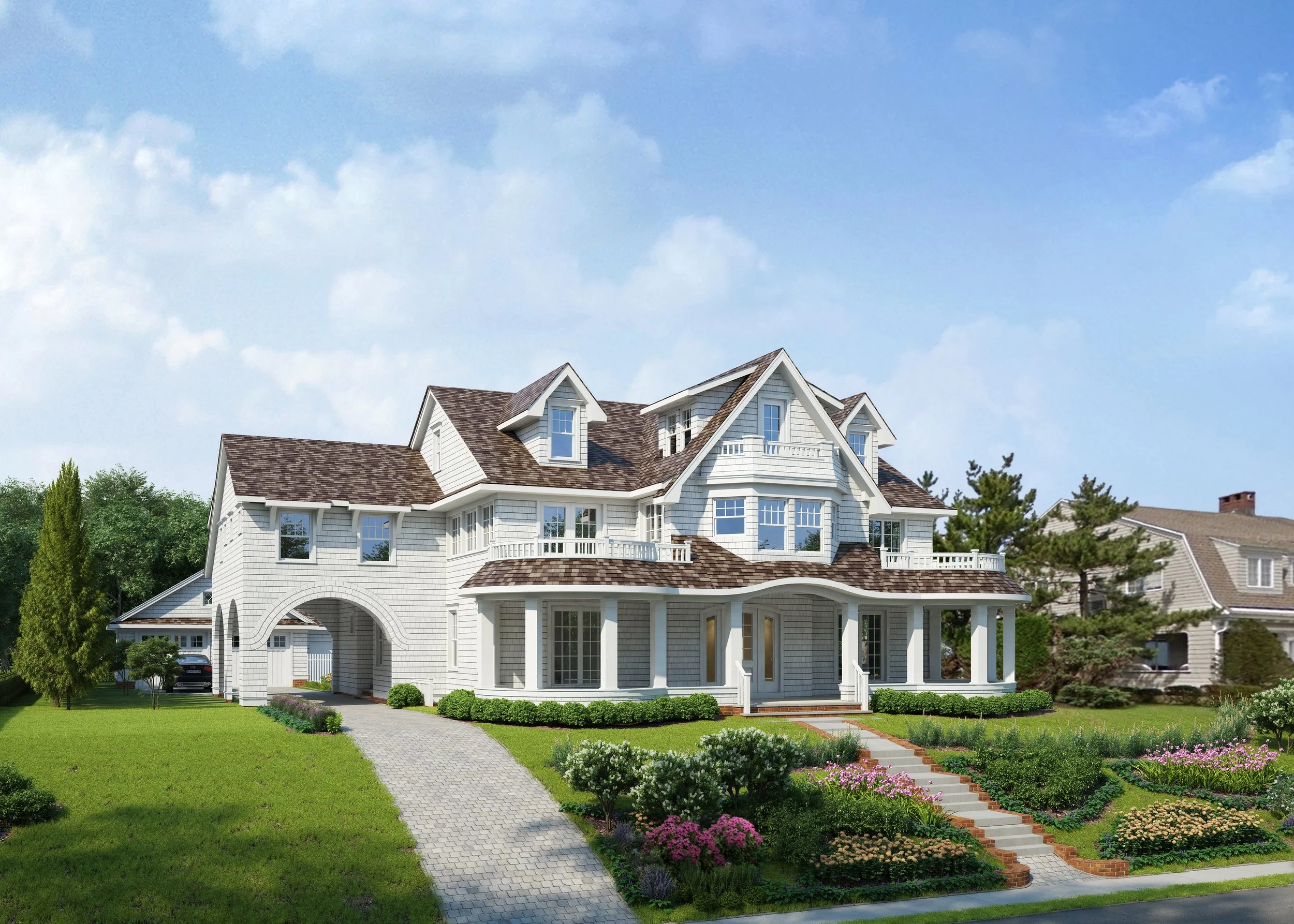 Large white house with multiple gabled roofs, a curved front porch with columns, and a landscaped front yard with flowers, bushes, and a paved walkway.