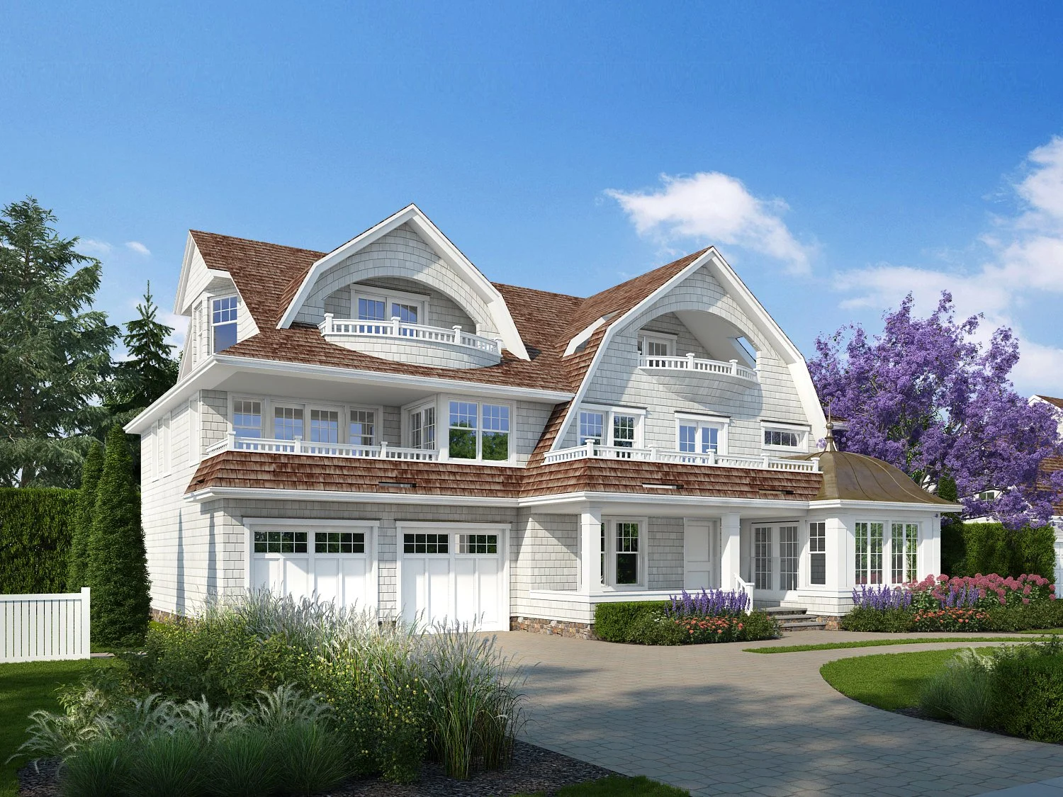 A large, white, multi-story house with a brown shingled roof and multiple balconies. The house has a front porch with steps leading to the entrance, surrounded by landscaped gardens and a paved walkway. There are trees and colorful flowers in the gar