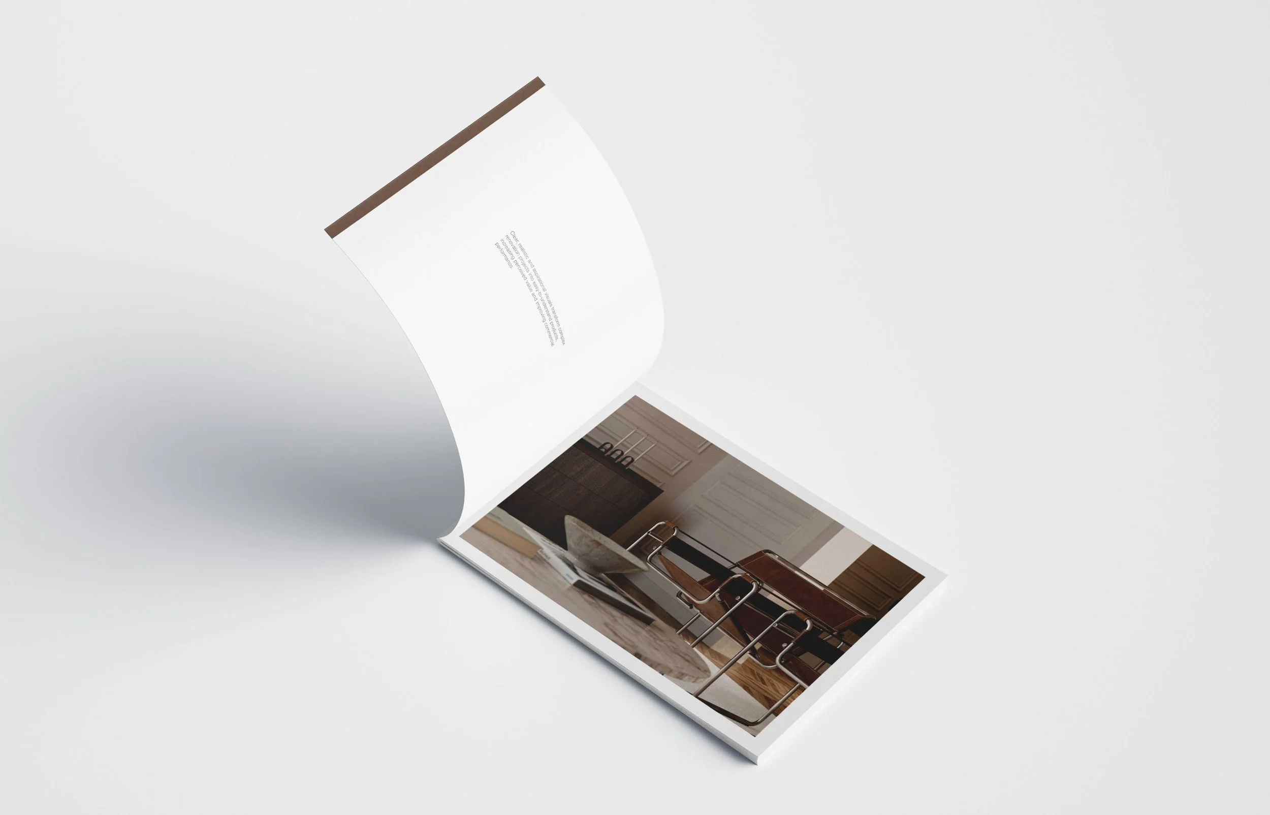 Open magazine showing a photograph of a modern kitchen with a glass bowl on a marble table and wooden chairs.