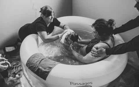 Person being baptized in an inflatable baptismal pool with several individuals assisting.