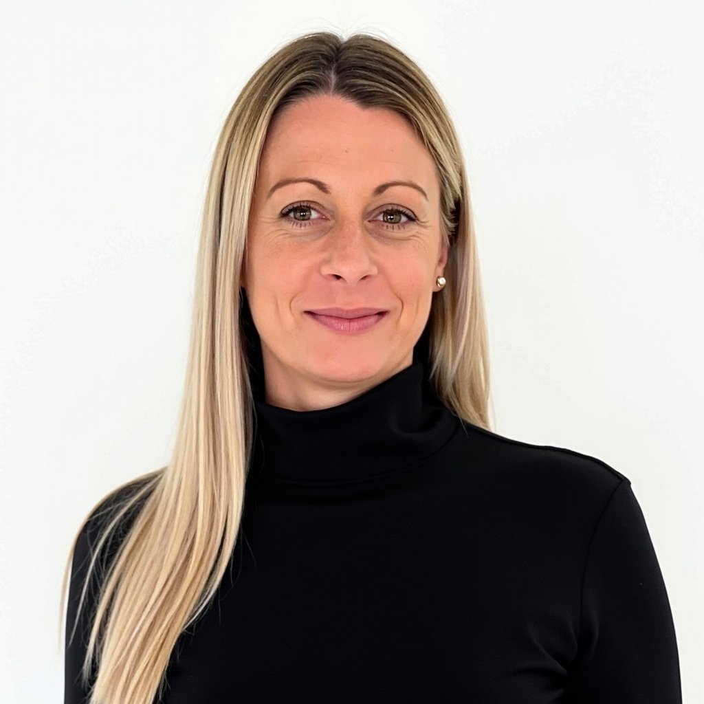A woman with long blonde hair wearing a black turtleneck and pearl earrings, smiling against a plain white background.