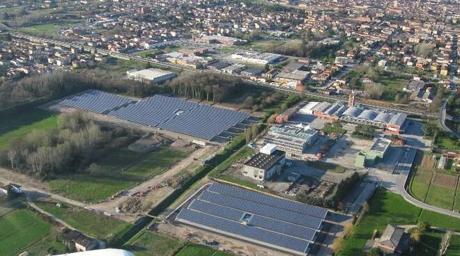 Immagine aerea di aree industriali e agricole con edifici e serre.