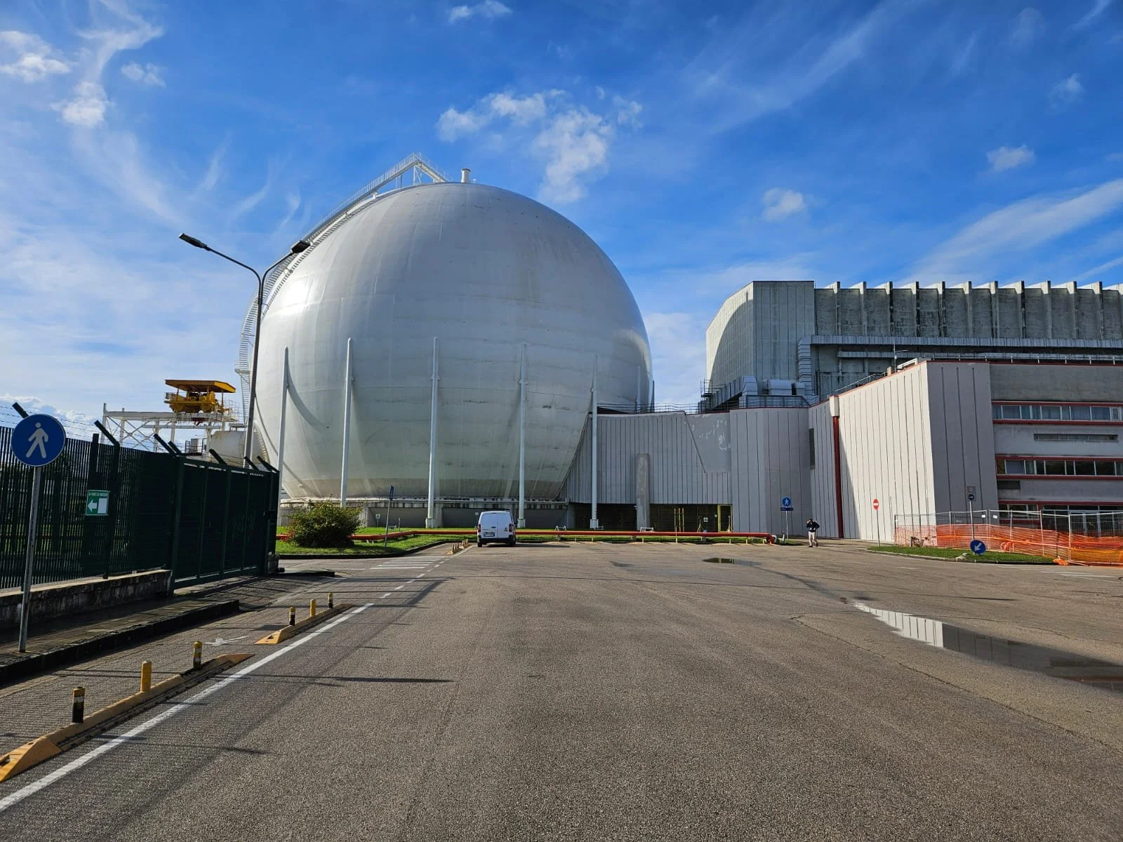 Impianto nucleare con una grande cupola bianca e strutture circostanti, cielo blu con poche nuvole.