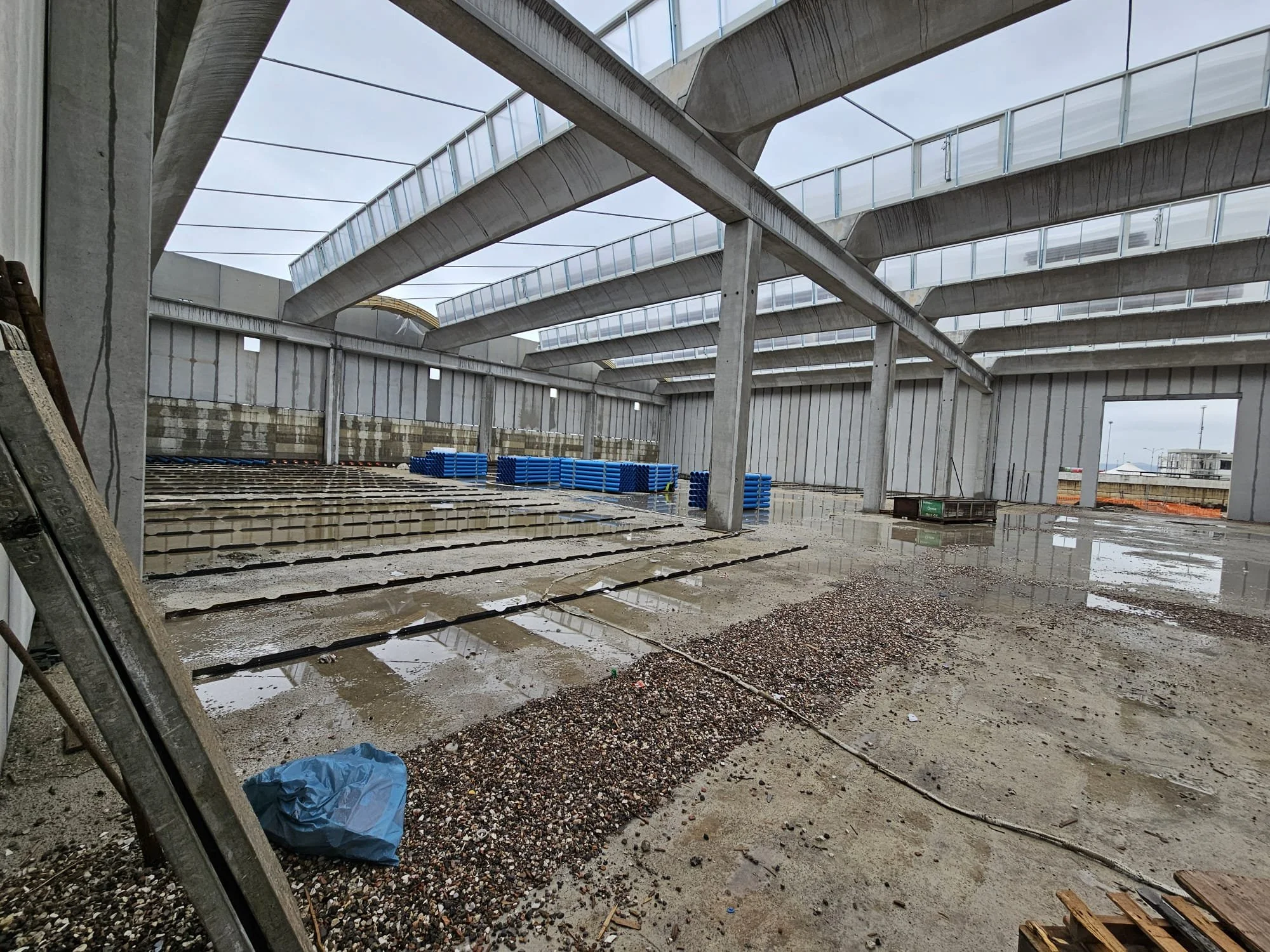 Interno di un edificio in costruzione con superficie bagnata e materiali da costruzione.