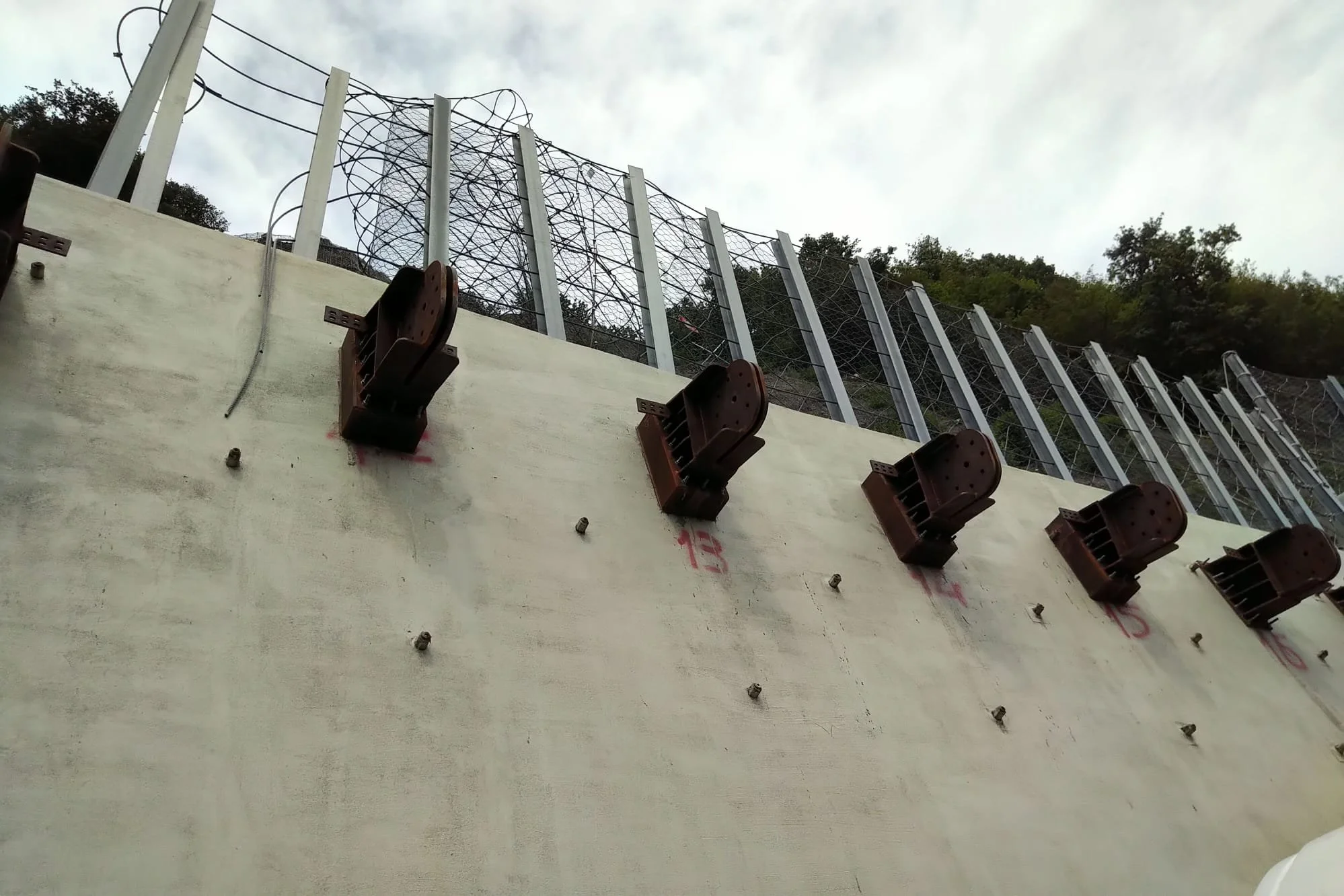 Dispositivo di sicurezza per un'opera di muratura con recinzione di filo spinato sulla cima, vista dall'angolazione.