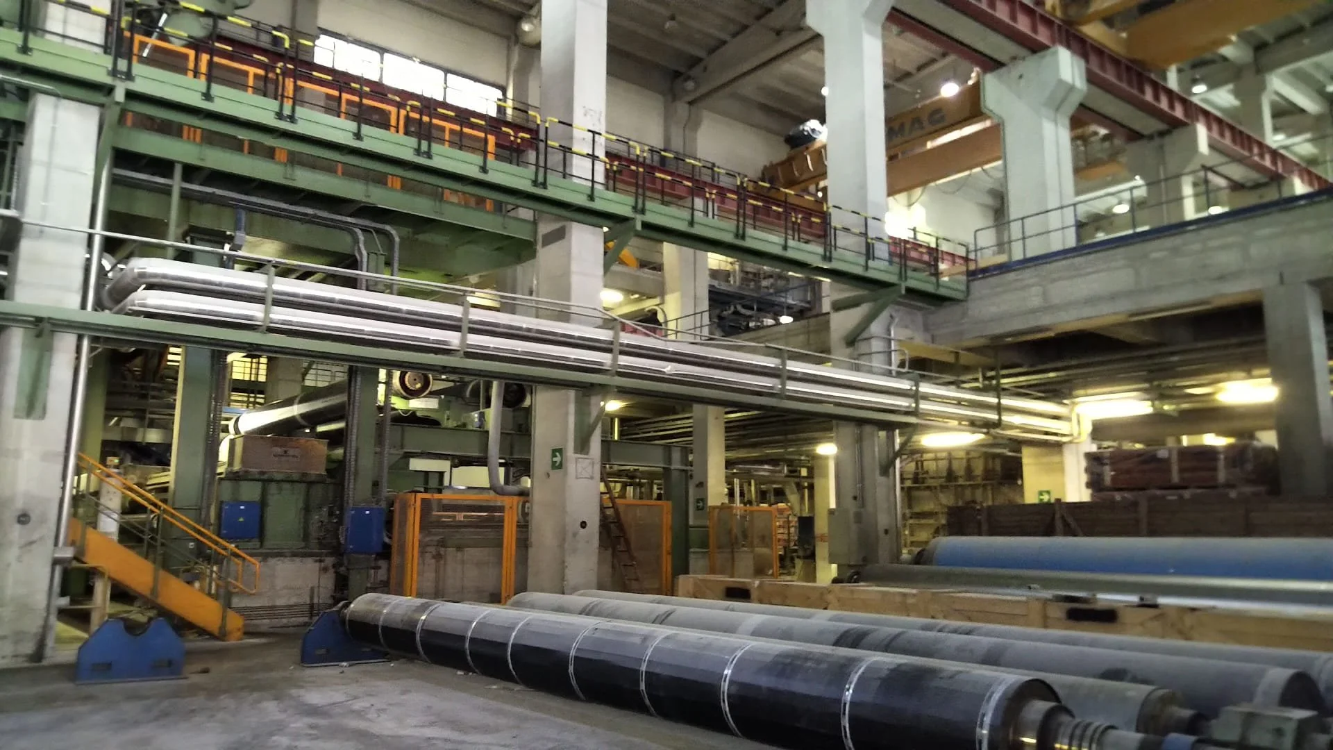 Interno di una fabbrica con macchinari industriali, tubi e strutture metalliche