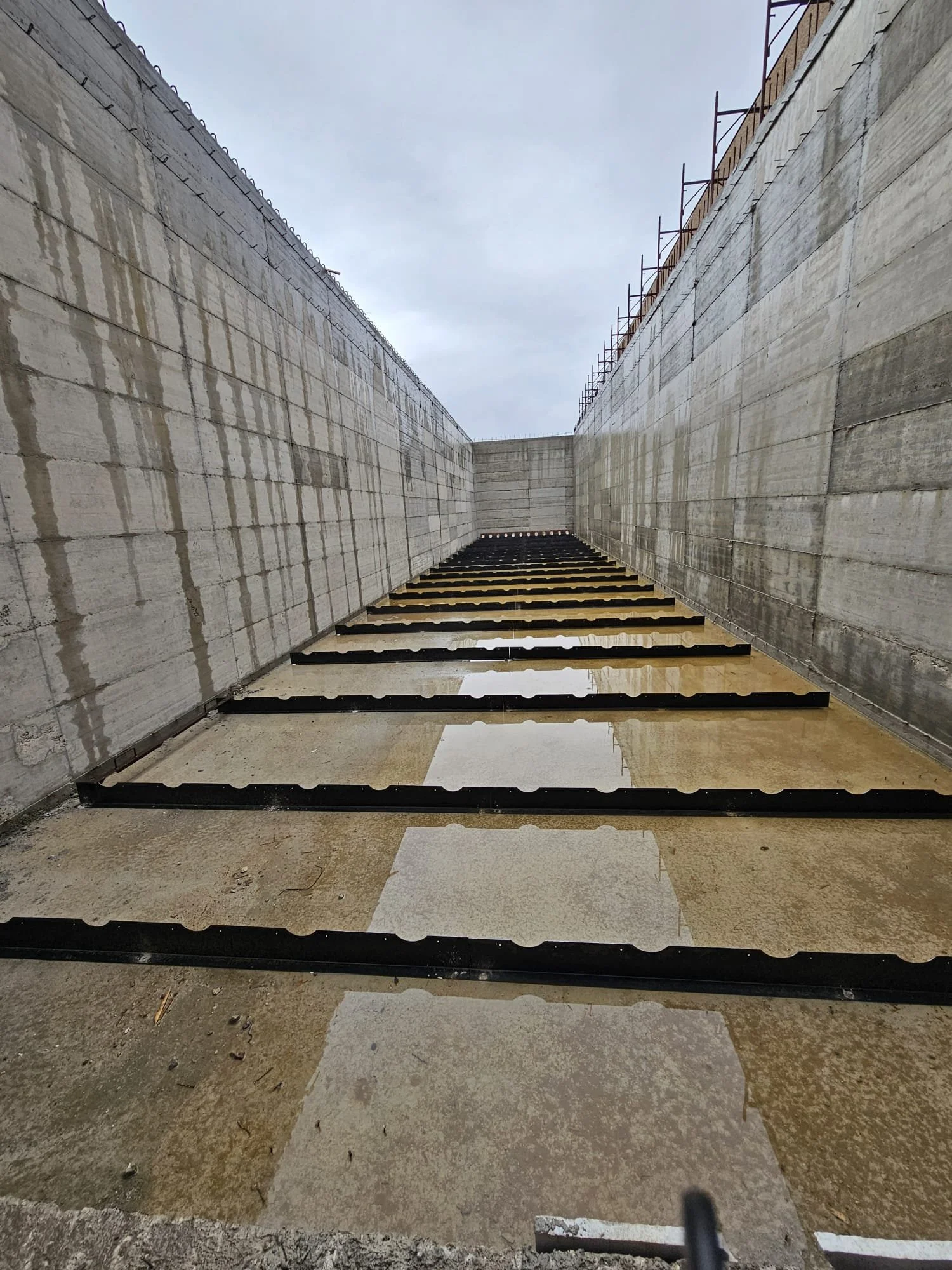 Parete di un cantiere in costruzione con lastroni di pietra e traversi di ferro.