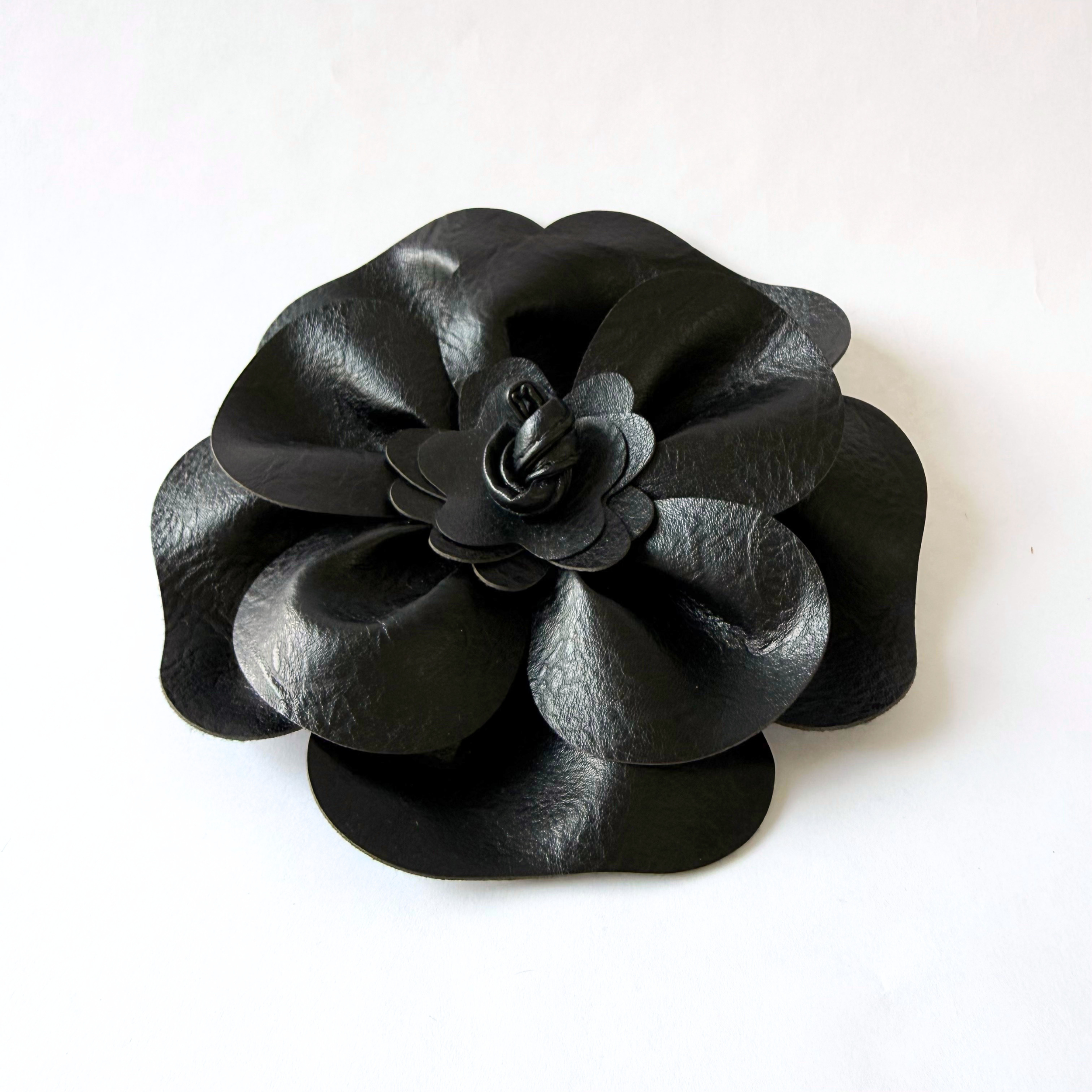 Close-up of oversized black leather floral brooch.