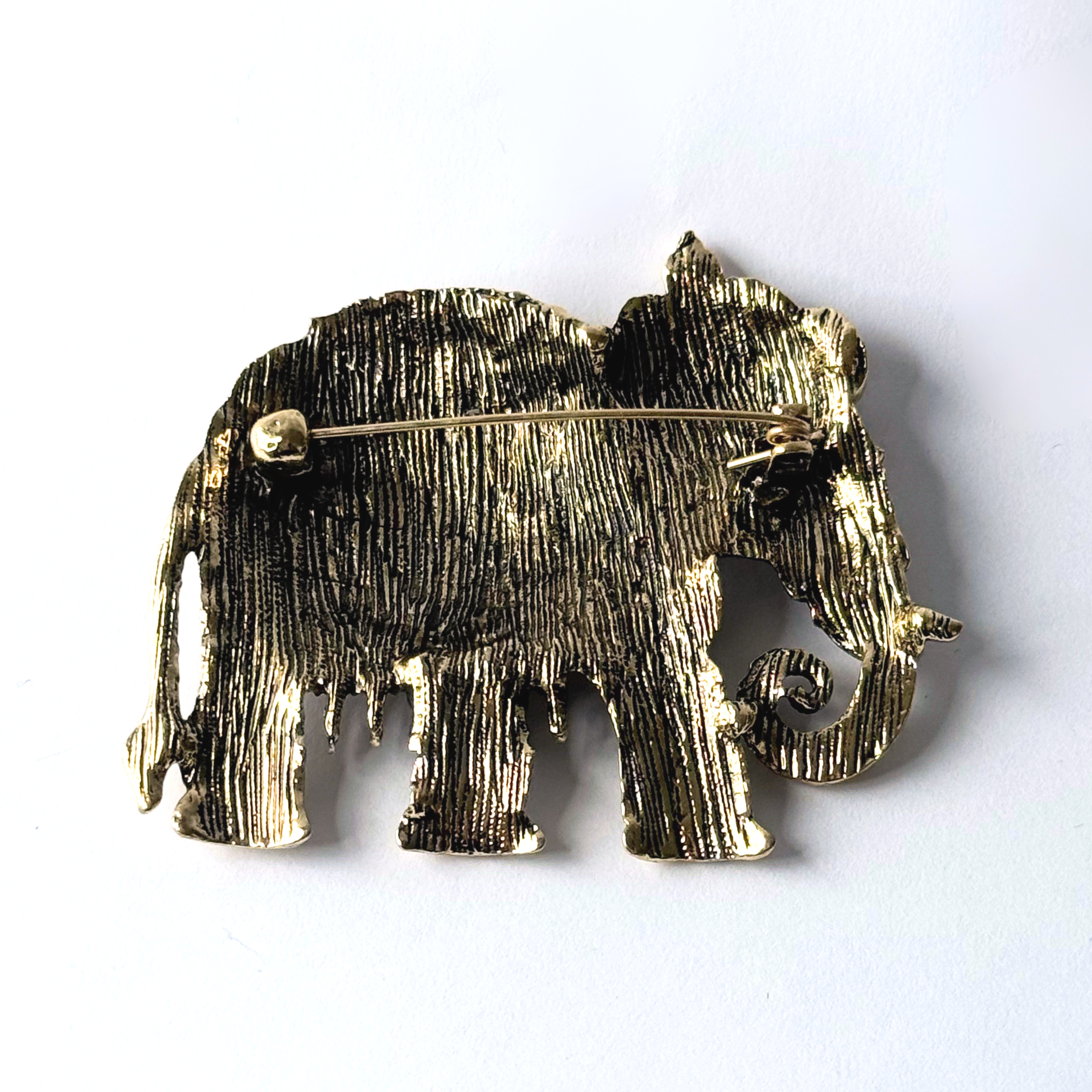 Close up of the back side of a matte gold toned elephant brooch.