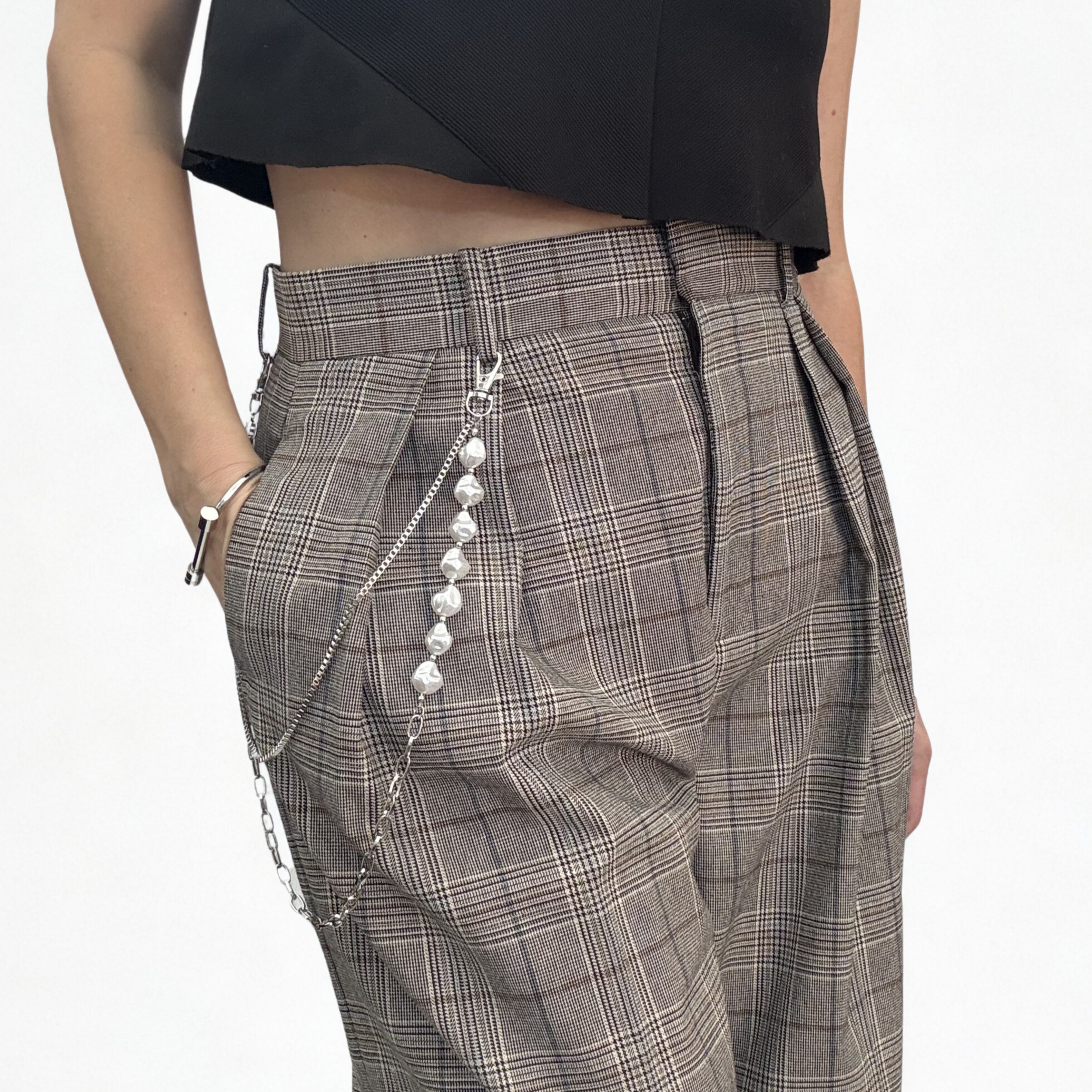 Close-up of a person's waist wearing plaid pants with a chain accessory and a black top.