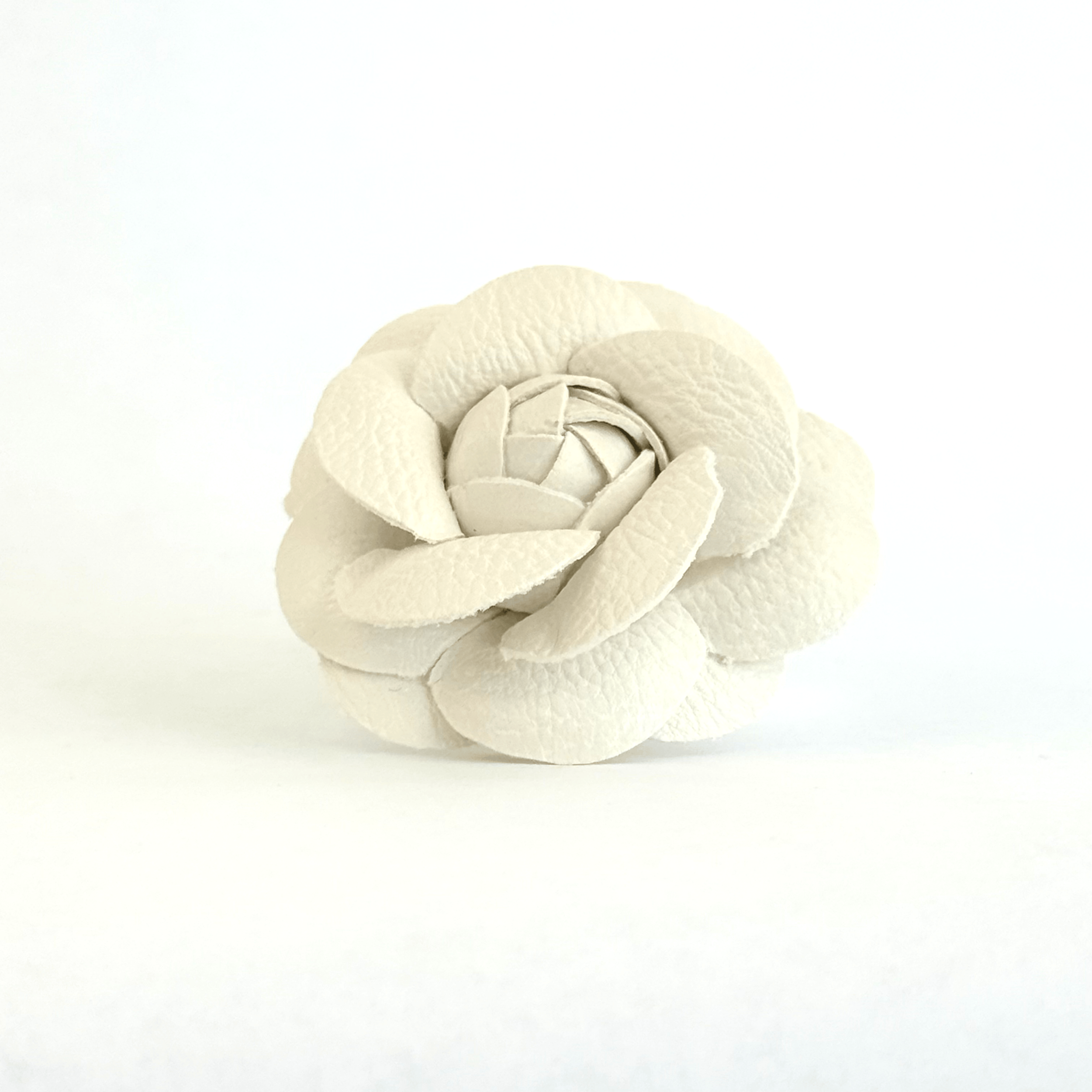 White faux leather rosette brooch with a rich, pebbled texture.