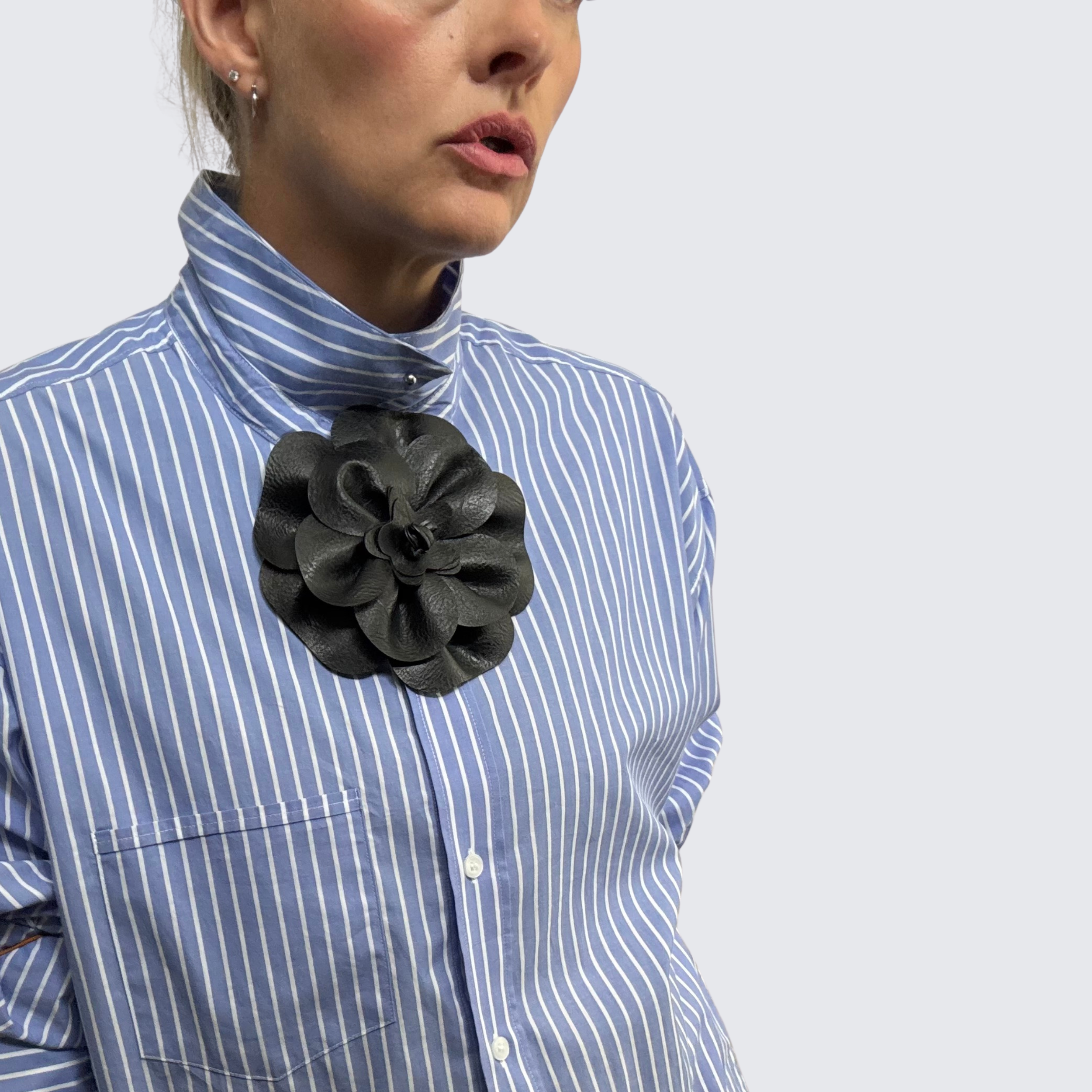 Woman wearing a blue and white striped shirt, accessorized with The Renegade Rose Brooch, a large black leather brooch.