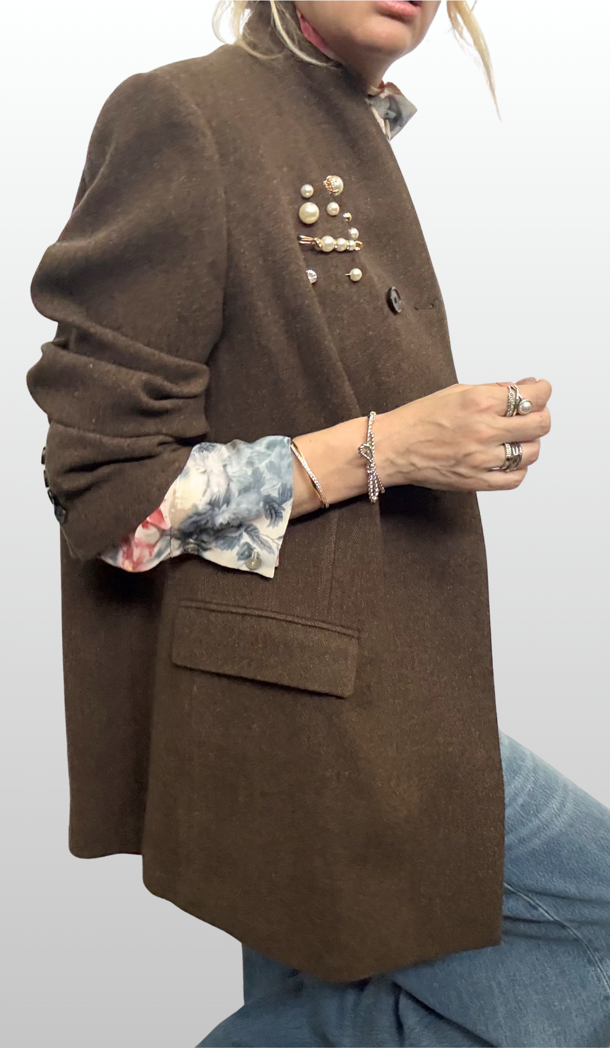 Woman wearing sheer floral shirt with brown blazer overtop. On the blazer lapel is a cluster of pearl pins from The Brooch House.