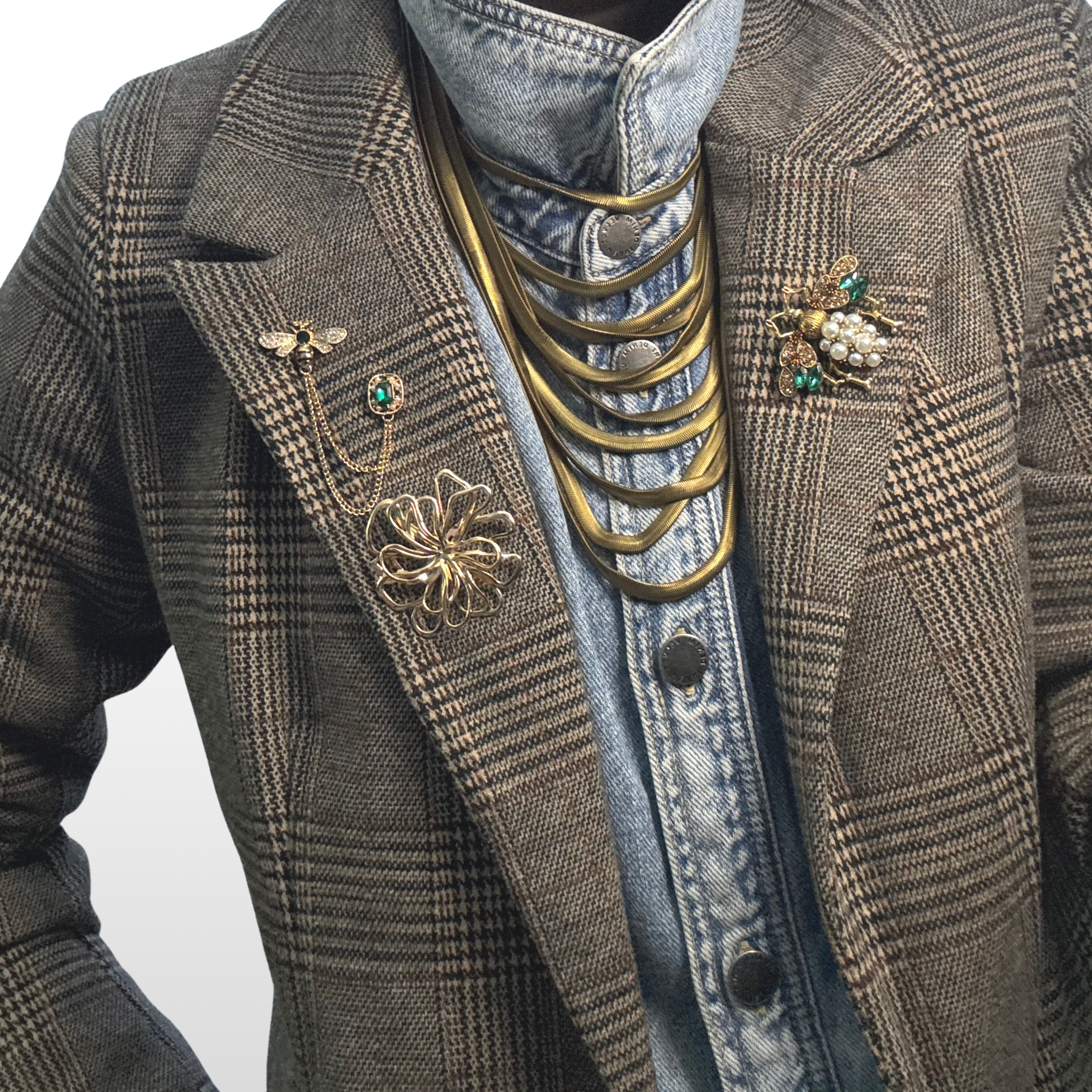 A close up of a woman wearing a plaid blazer with three gold brooches on her lapel..