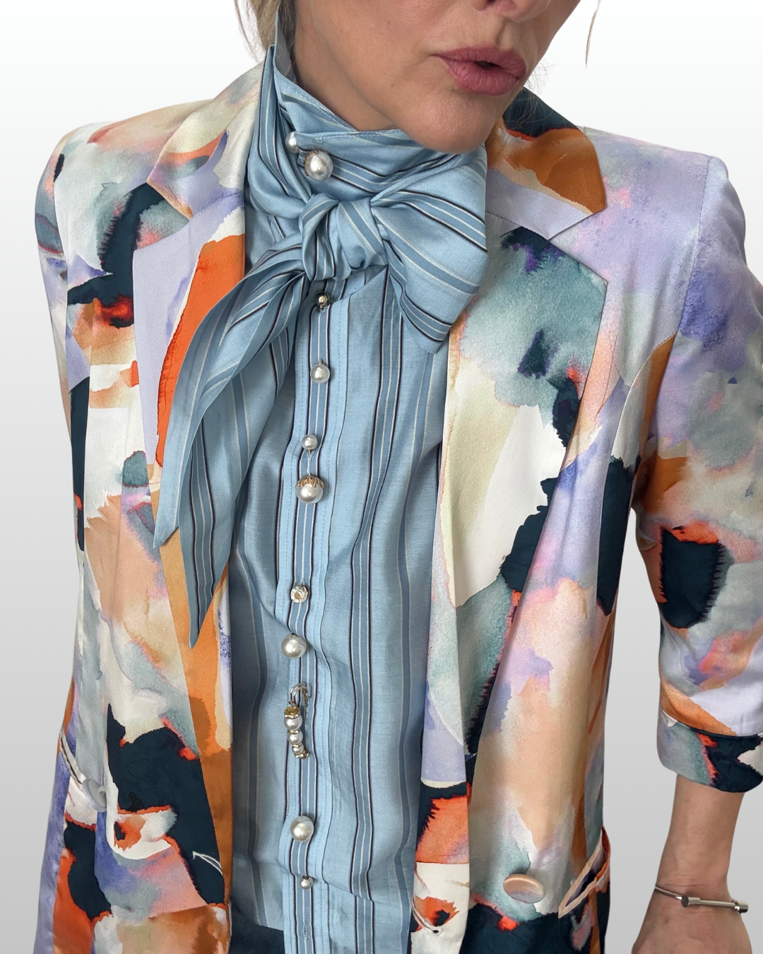 Woman wearing blue striped button up featuring double sided pearl pins as custom buttons.  A silk floral jacket is layered over top.