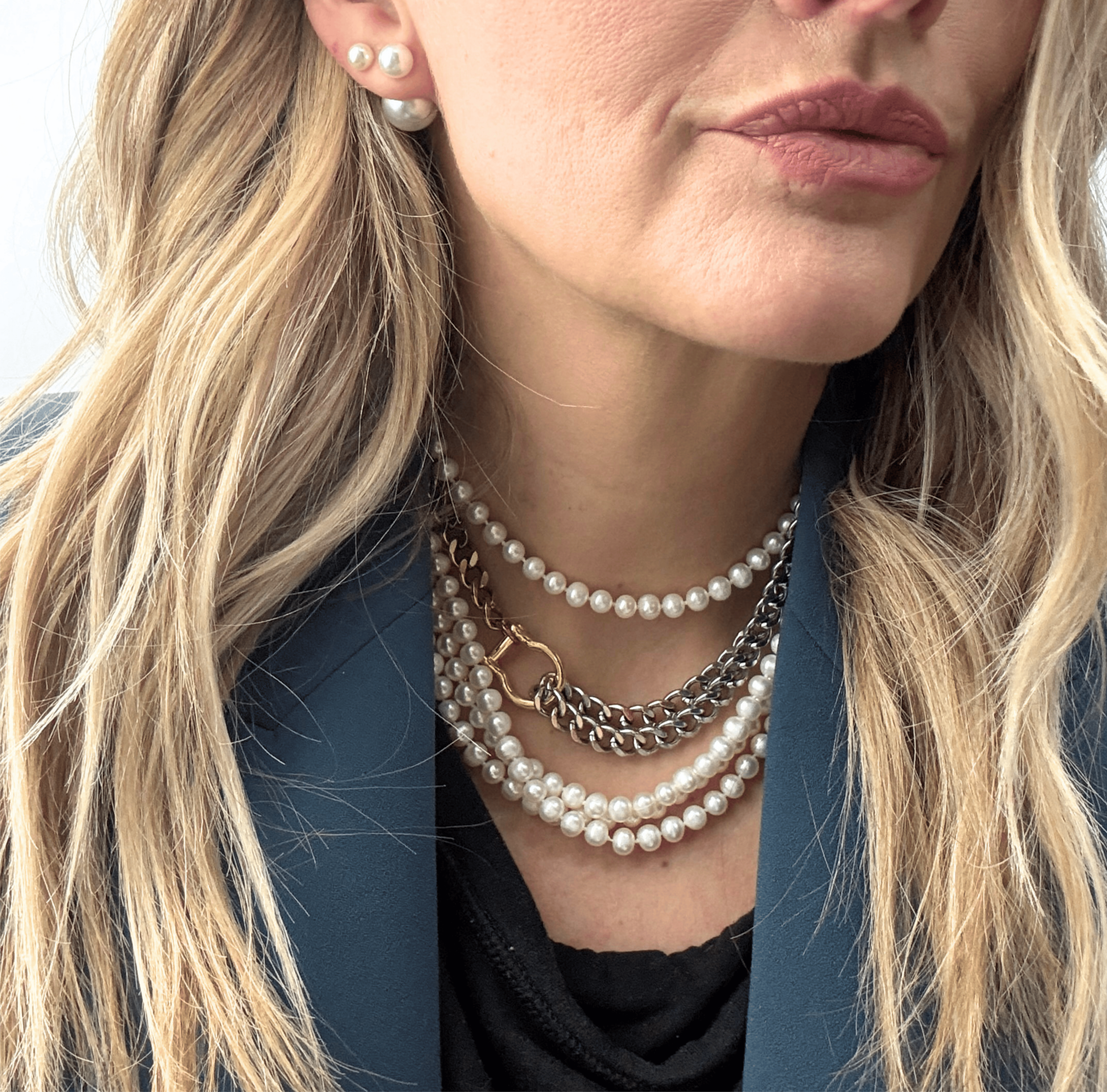 A bold, carabiner-style junction on a substantial, high-shine curb link chain, layered with classic pearls.