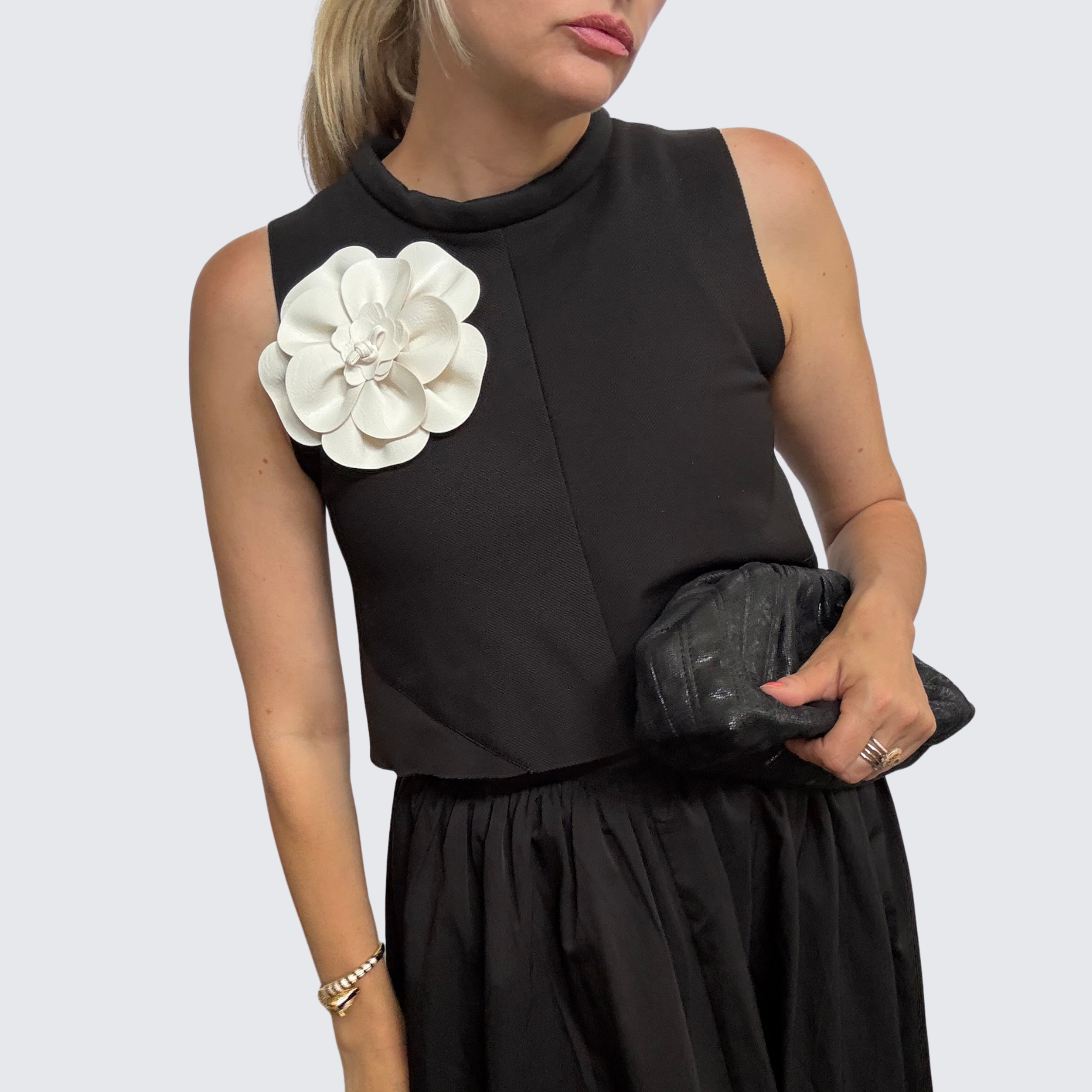Woman wearing black shell top and black skirt accessorized with The Renegade Rose Brooch, a large cream coloured leather brooch.