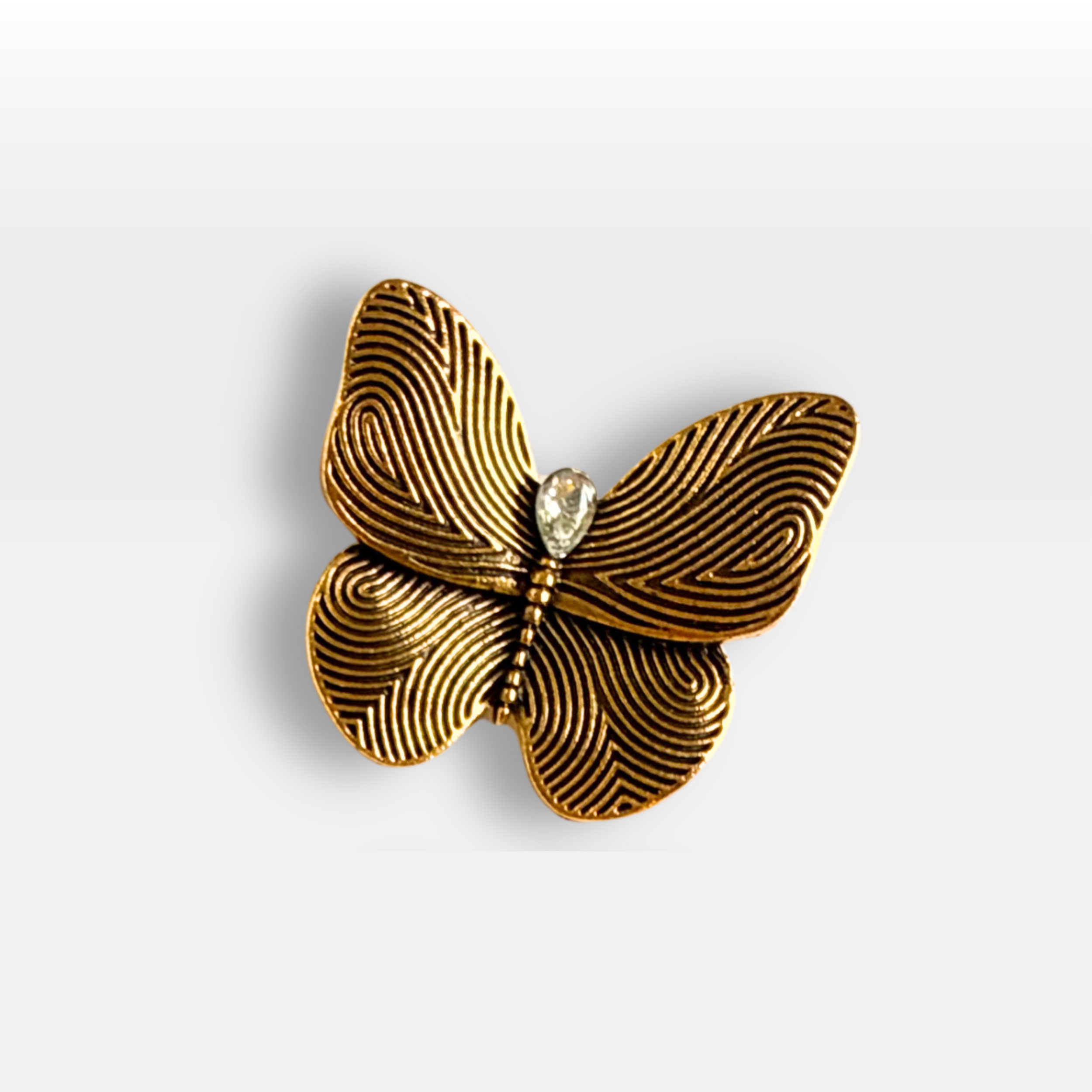 Colse up of small golden butterfly brooch with a crystal in the centre.