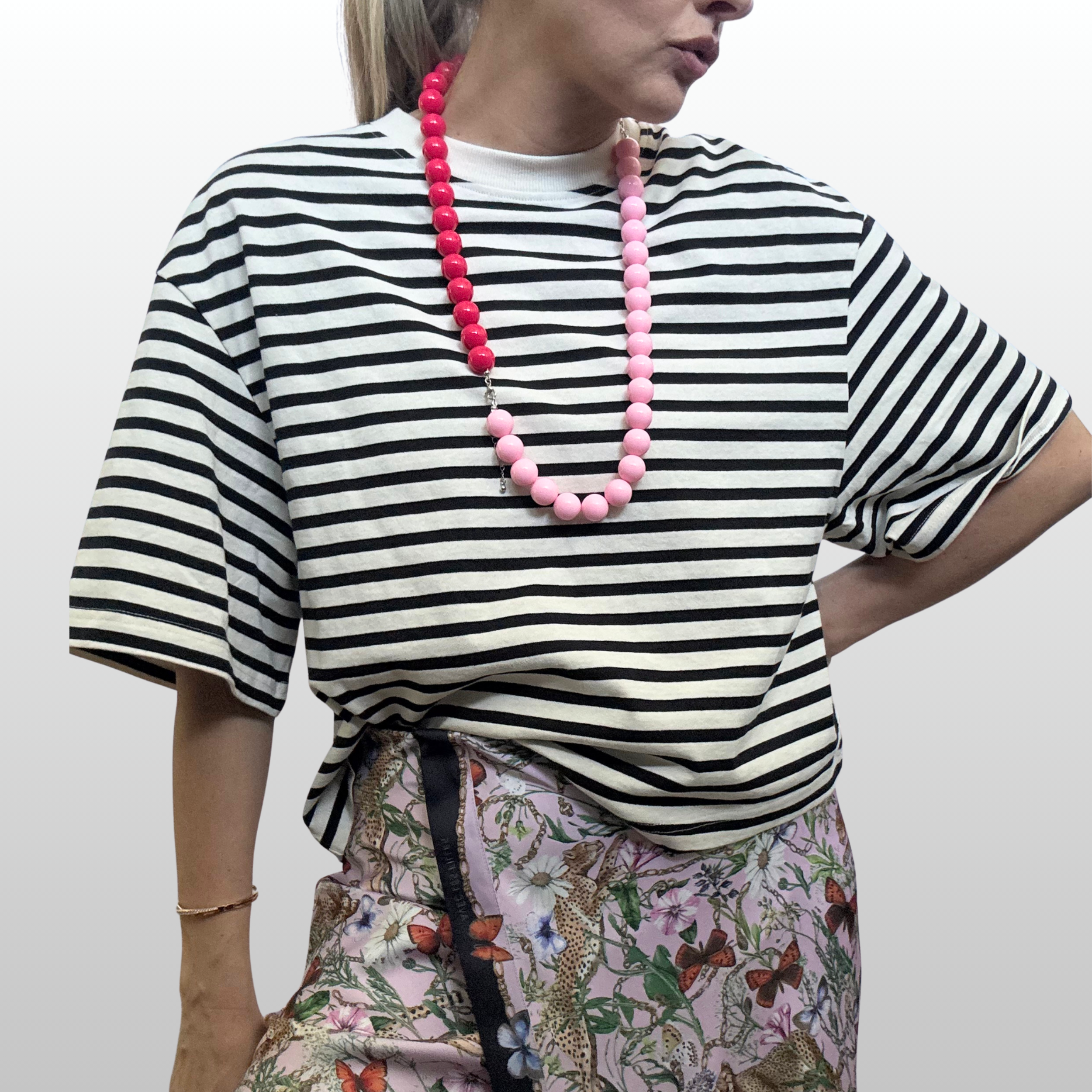 Woman wearing black and white striped t-shirt and a long strand of bright pink and light pink resin beads.