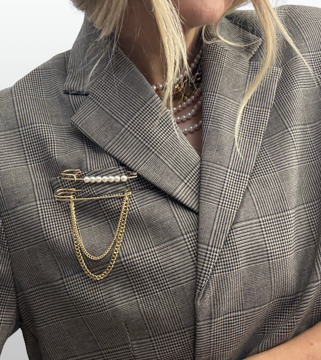 Close-up of a classic blazer lapel styled with a fluid draped pearl brooch, showing contrast against structured fabric.