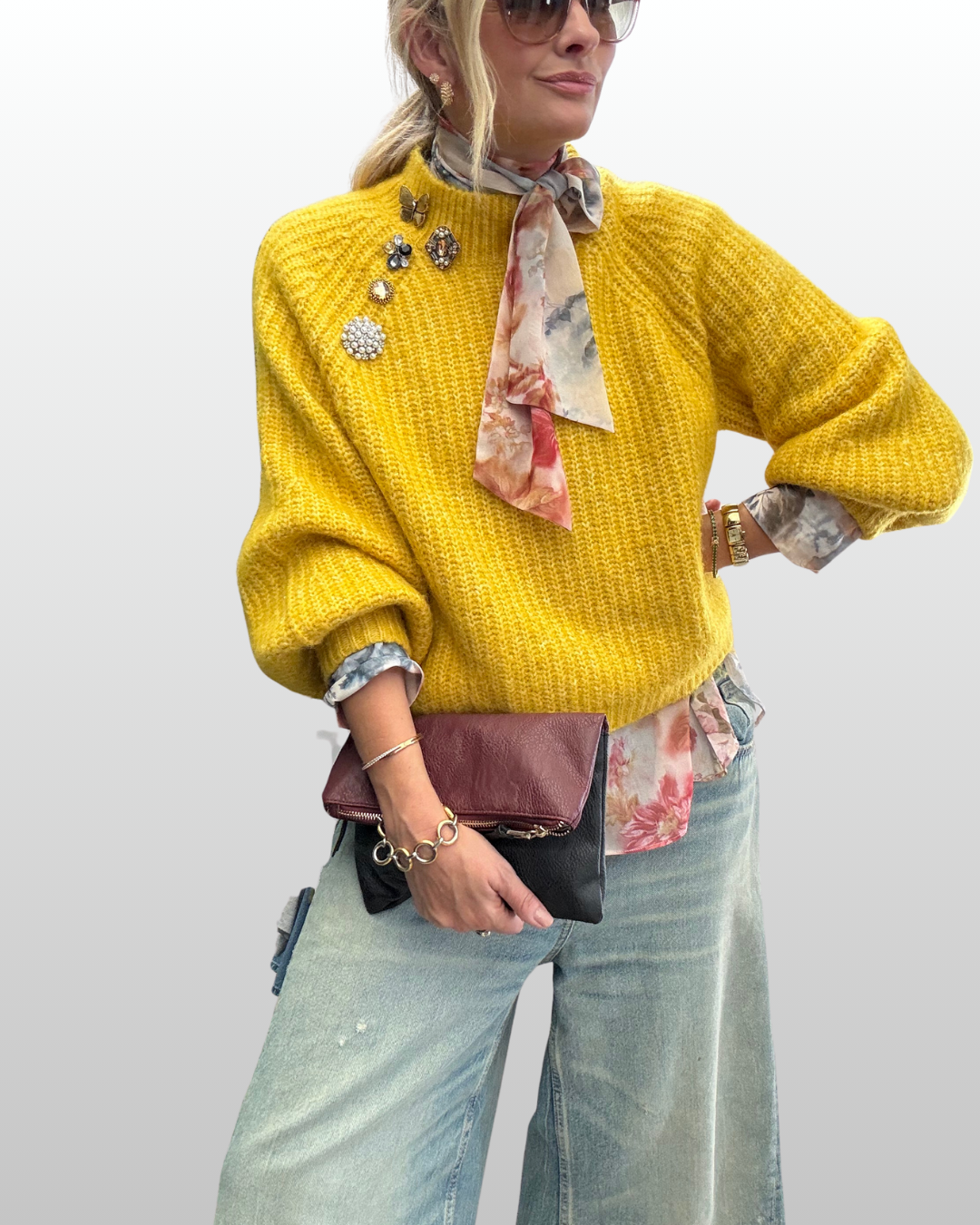 Cascading stack of fall brooches arranged diagonally along a yellow ribbed sweater seam.