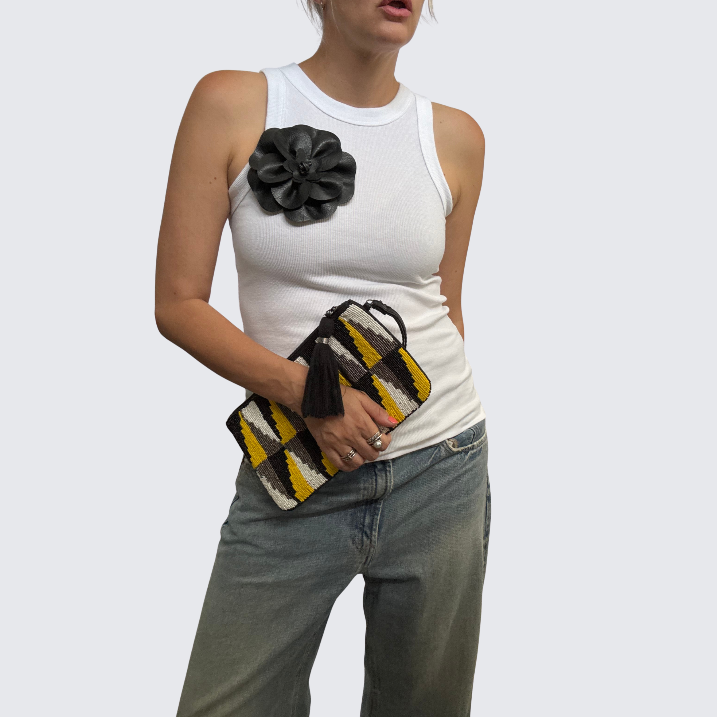 Woman wearing a simple white ribbed tank and baggy denim, accessorized with The Renegade Rose Brooch, a large black leather brooch.